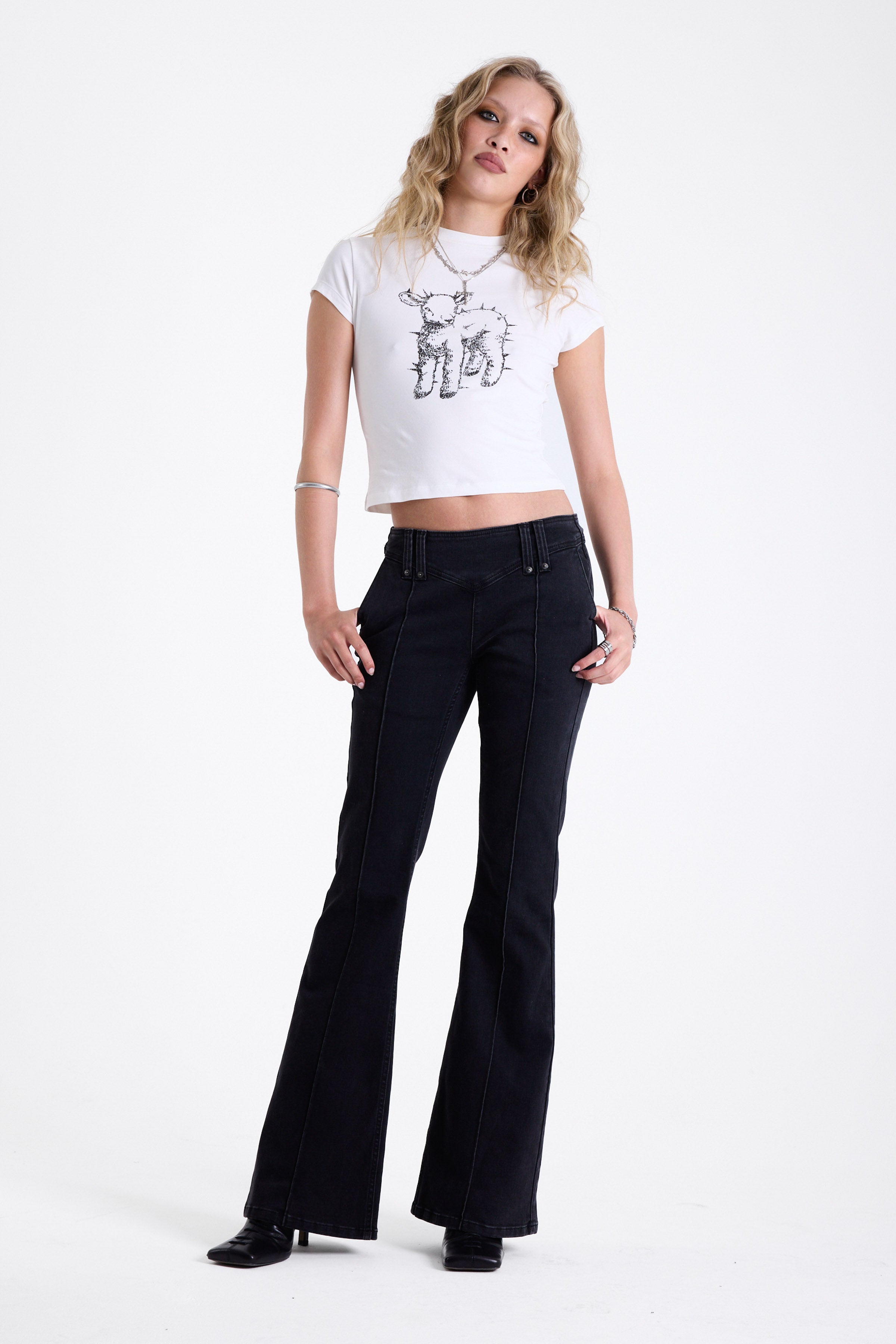 Washed black seam detail flare jeans with studs at waistband and back zip, worn by model.