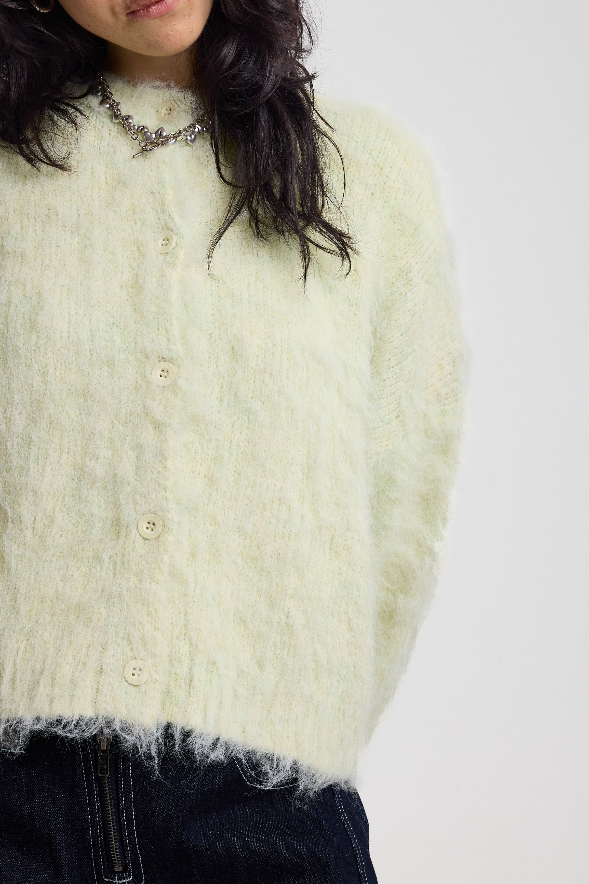 Close up showing fuzzy fluffy knit on ale green cardigan with gothic Baby slogan on back, worn by model