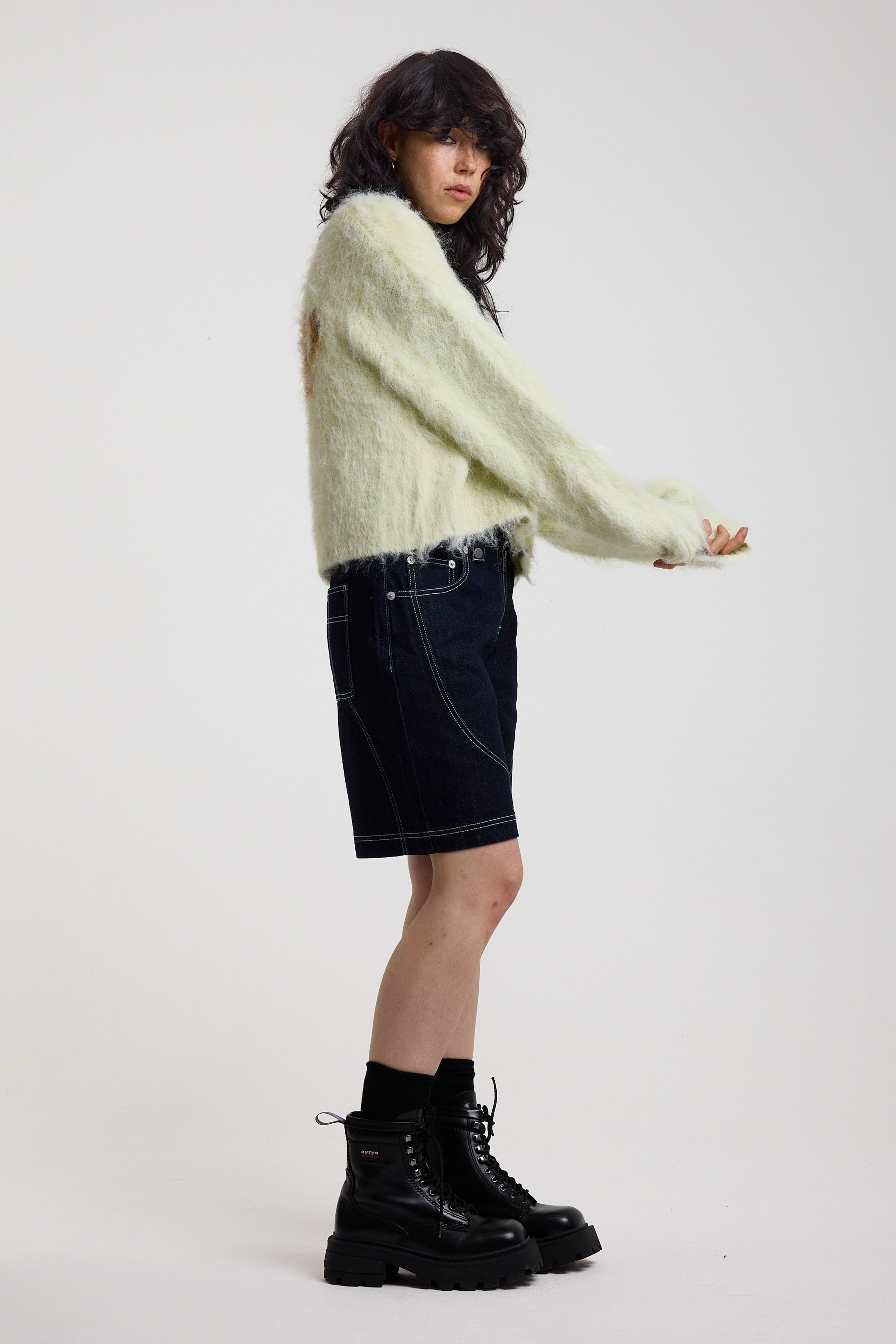 Pale green fuzzy knit cardigan with gothic Baby slogan on back, worn by model