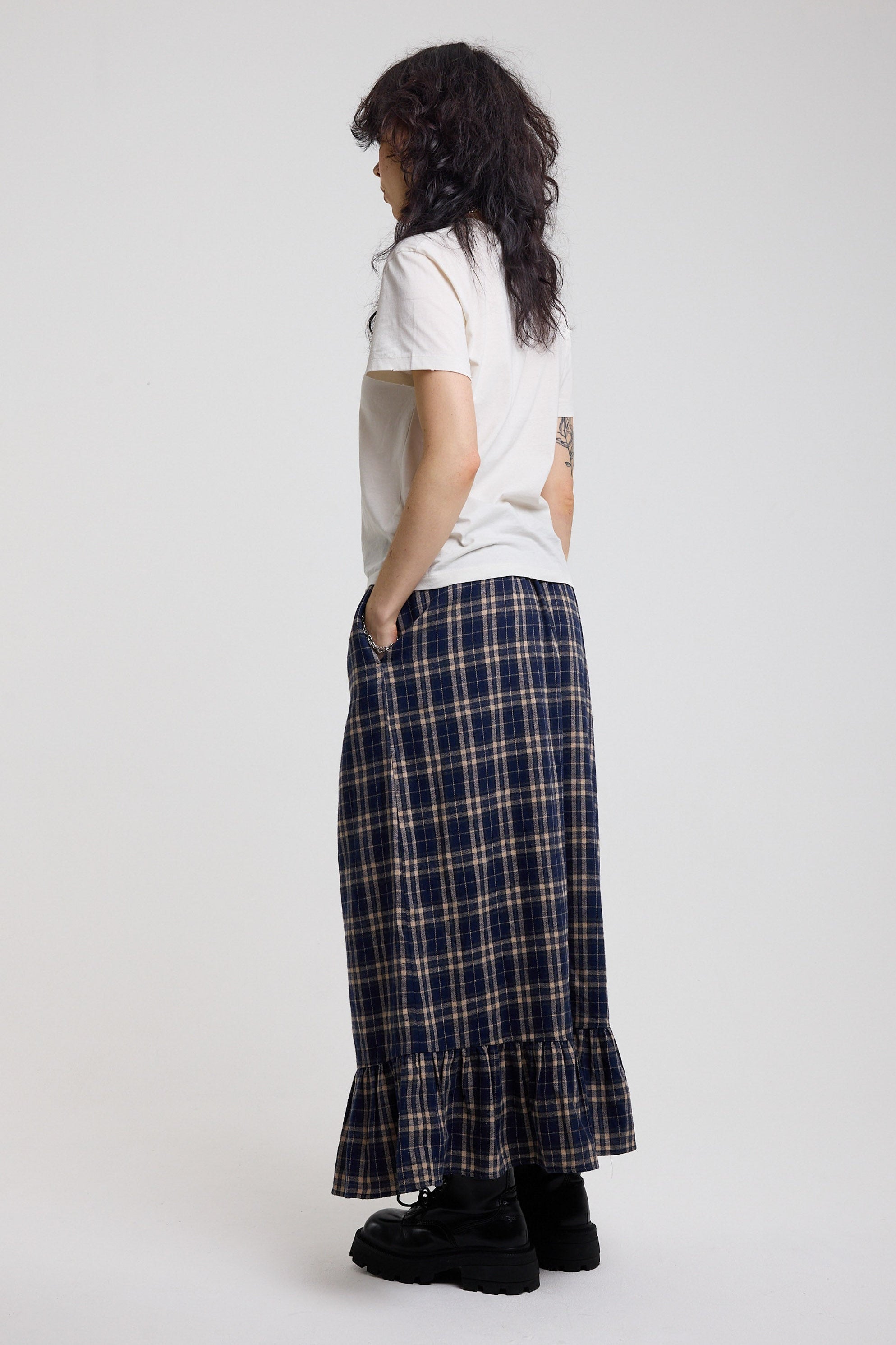 Side image of blue and yellow check maxi skirt with peplum hem showing pocket detail, worn by model
