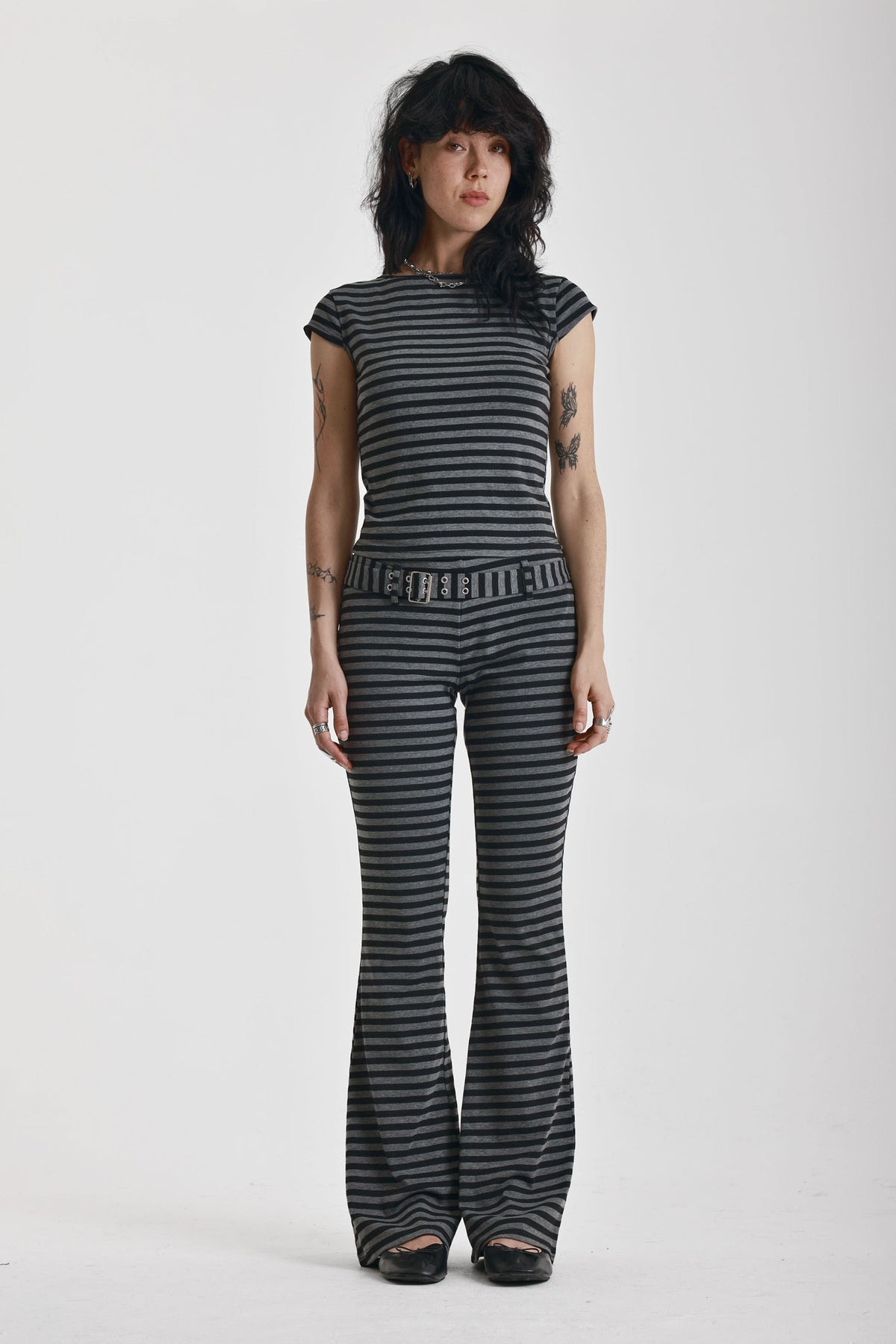 Grey and black stripe jersey flare trousers with eyelet belt, worn by model