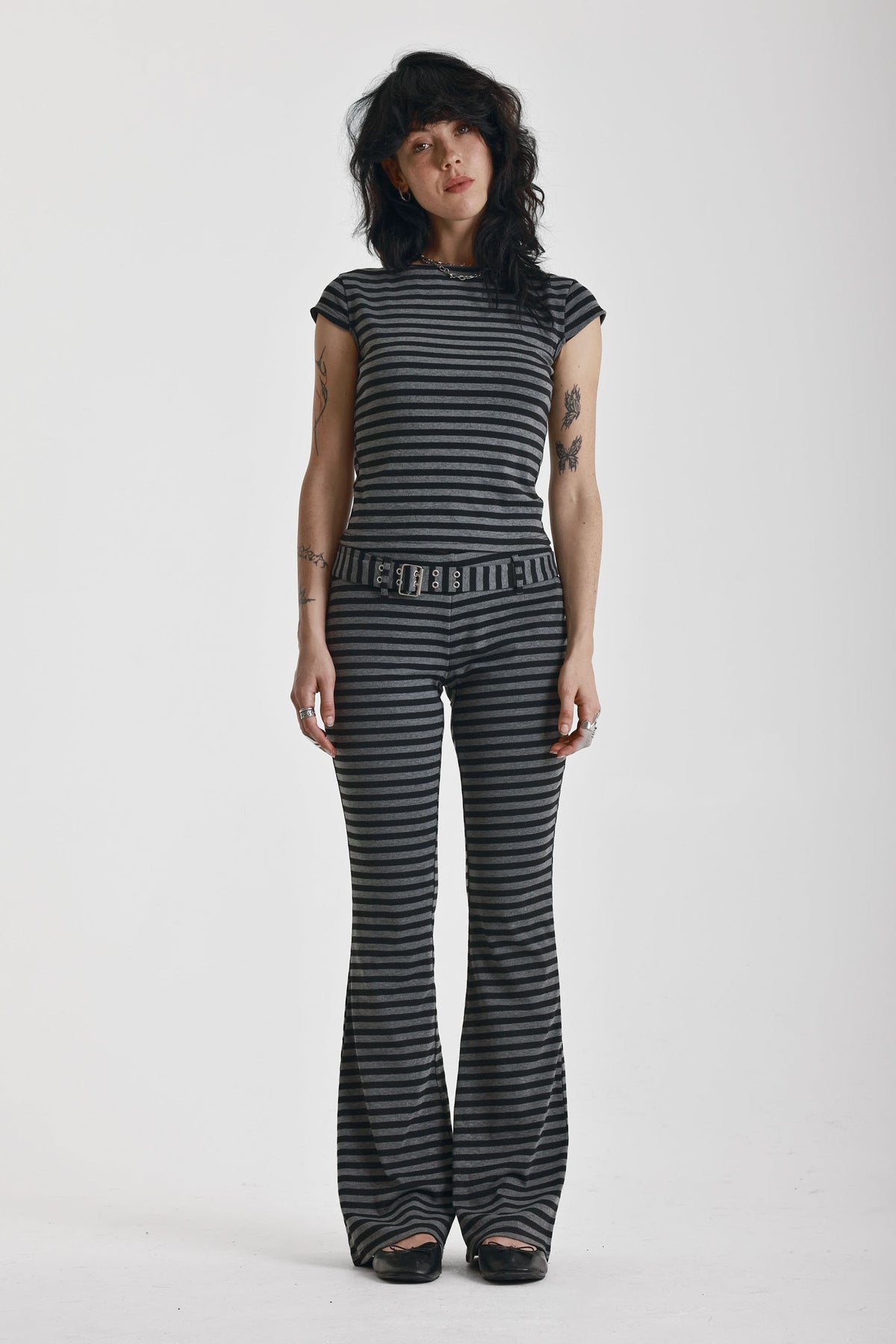 Grey and black stripe jersey flare trousers with eyelet belt, worn by model