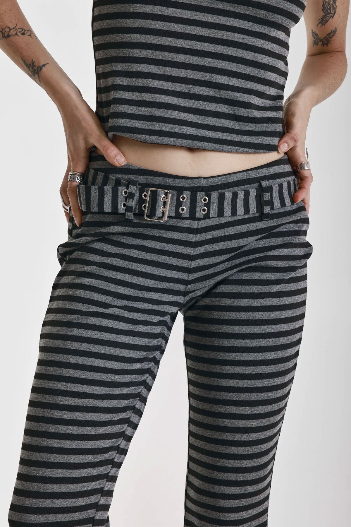 Grey and black stripe jersey flare trousers with eyelet belt, worn by model