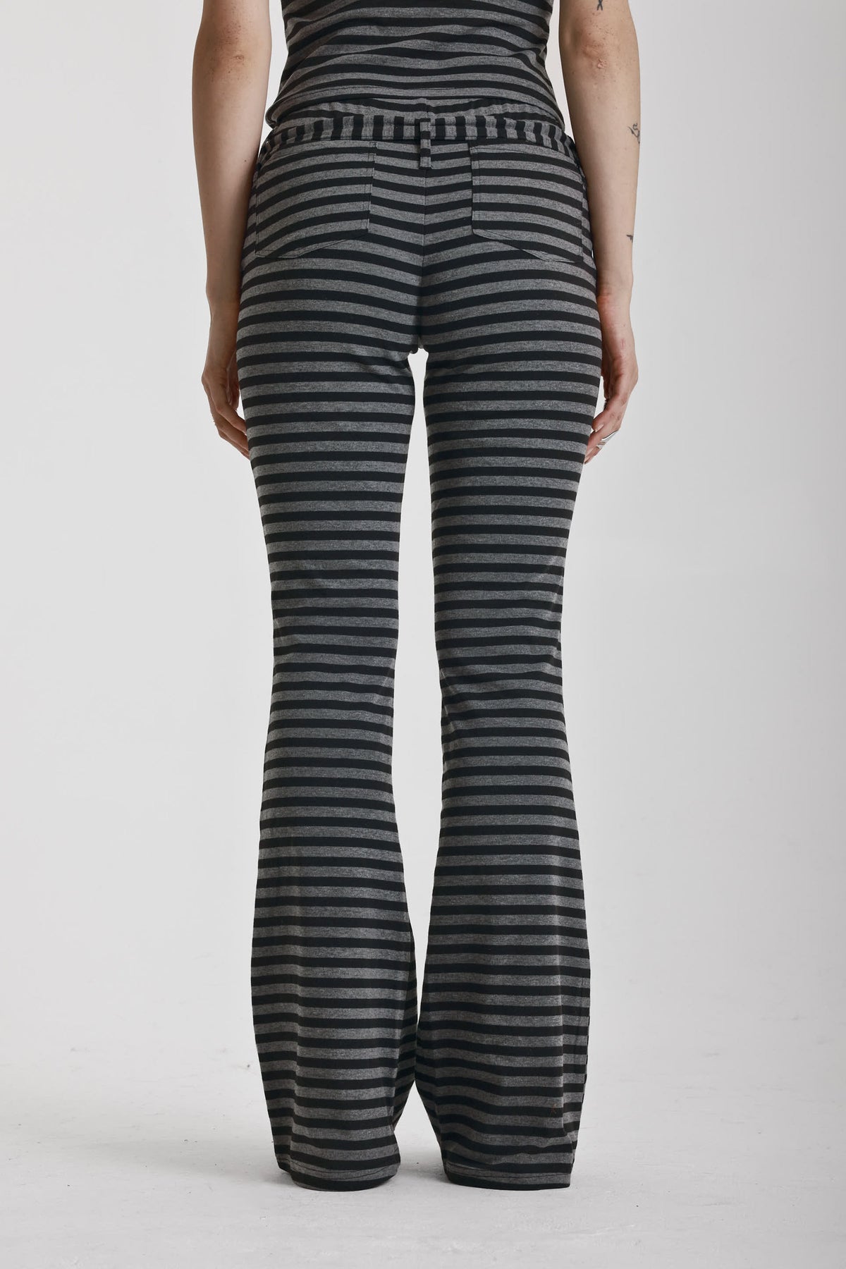 Grey and black stripe jersey flare trousers with eyelet belt, worn by model