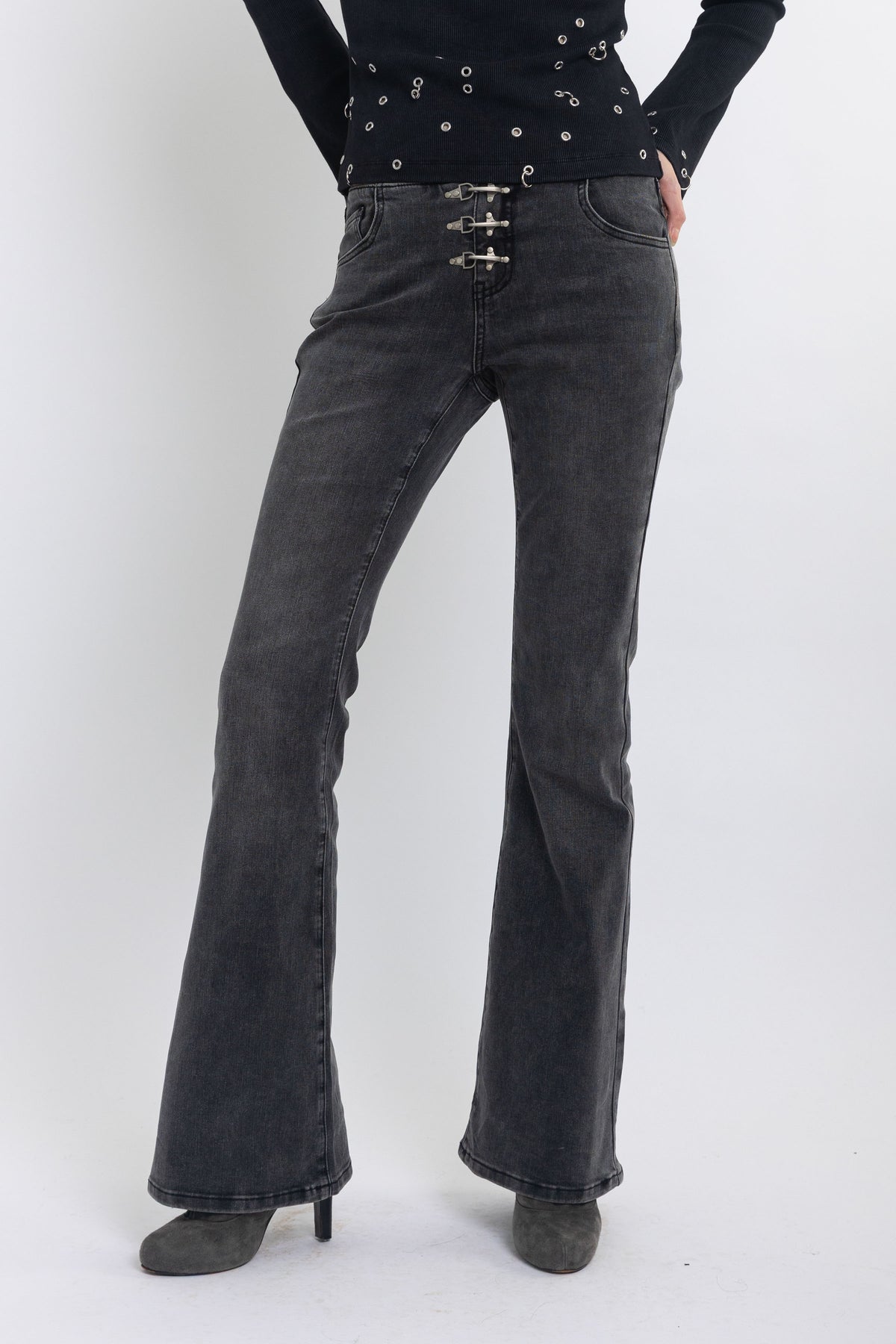 Washed black low rise flare jeans with no waistband and silver clasp hardware, worn by model
