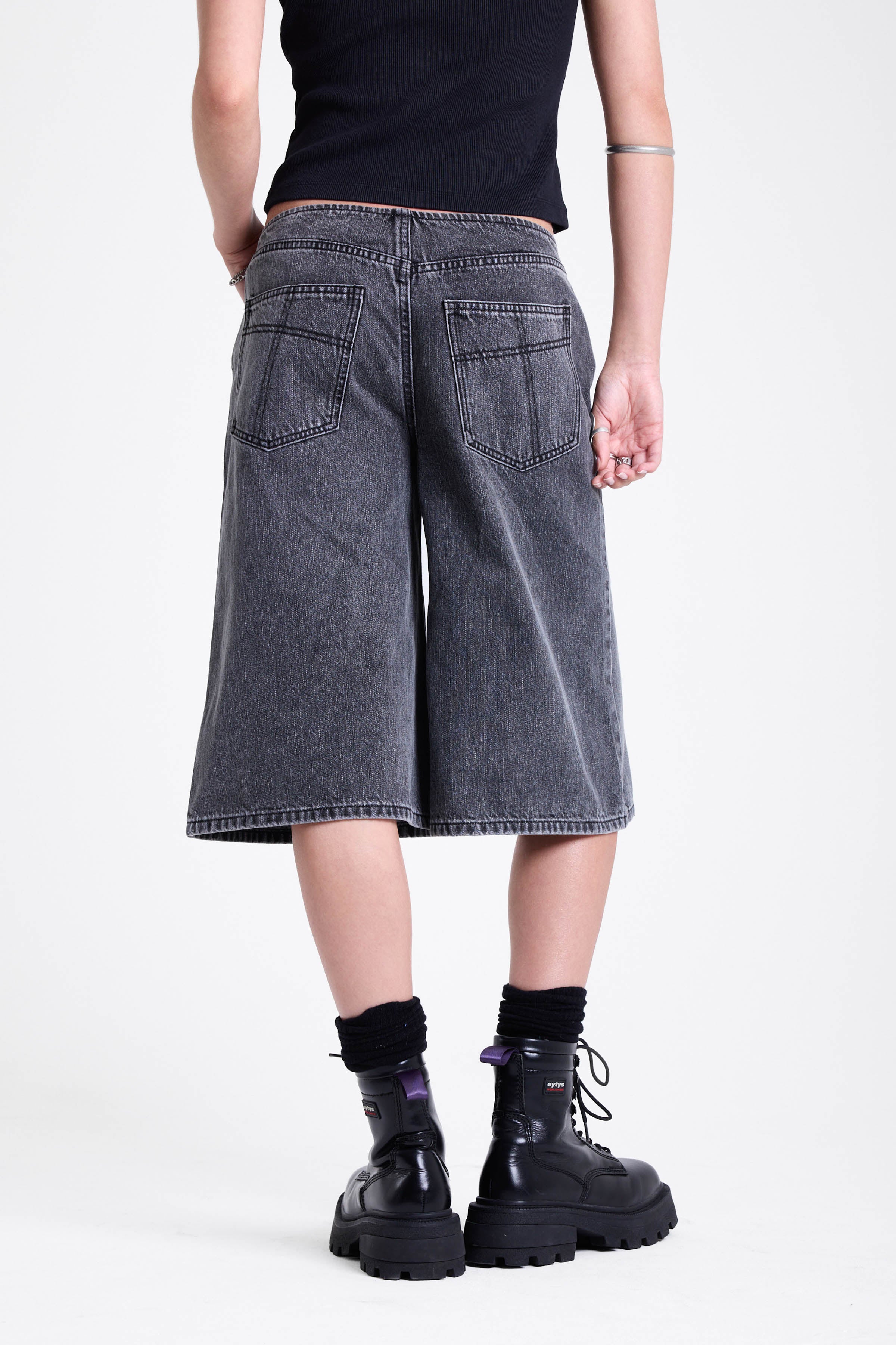 Washed black longline oversized denim jorts with no waistband and silver latch clasp detail, worn by model