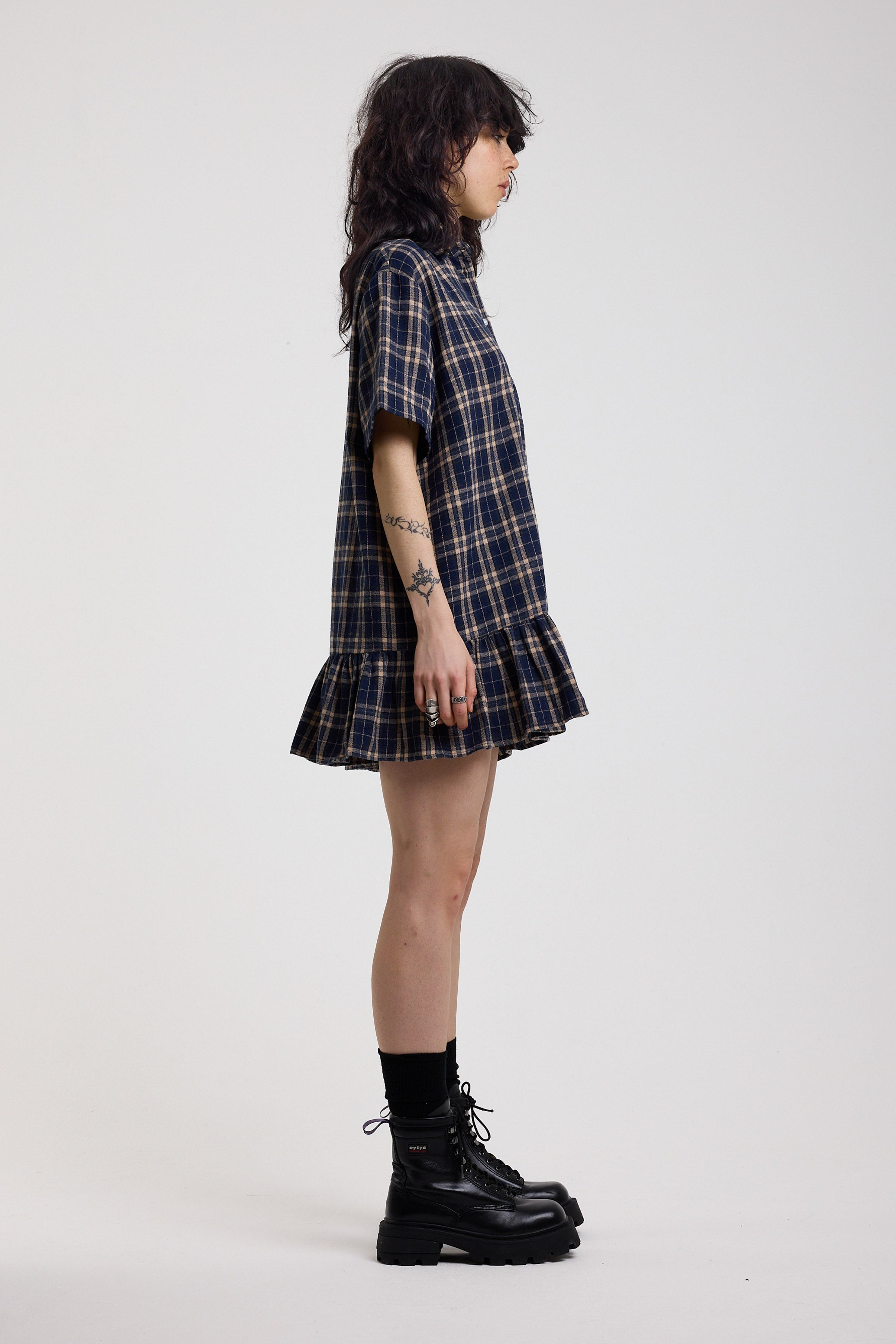 Side image of navy and yellow check shirt style mini dress with peplum hem, worn by model