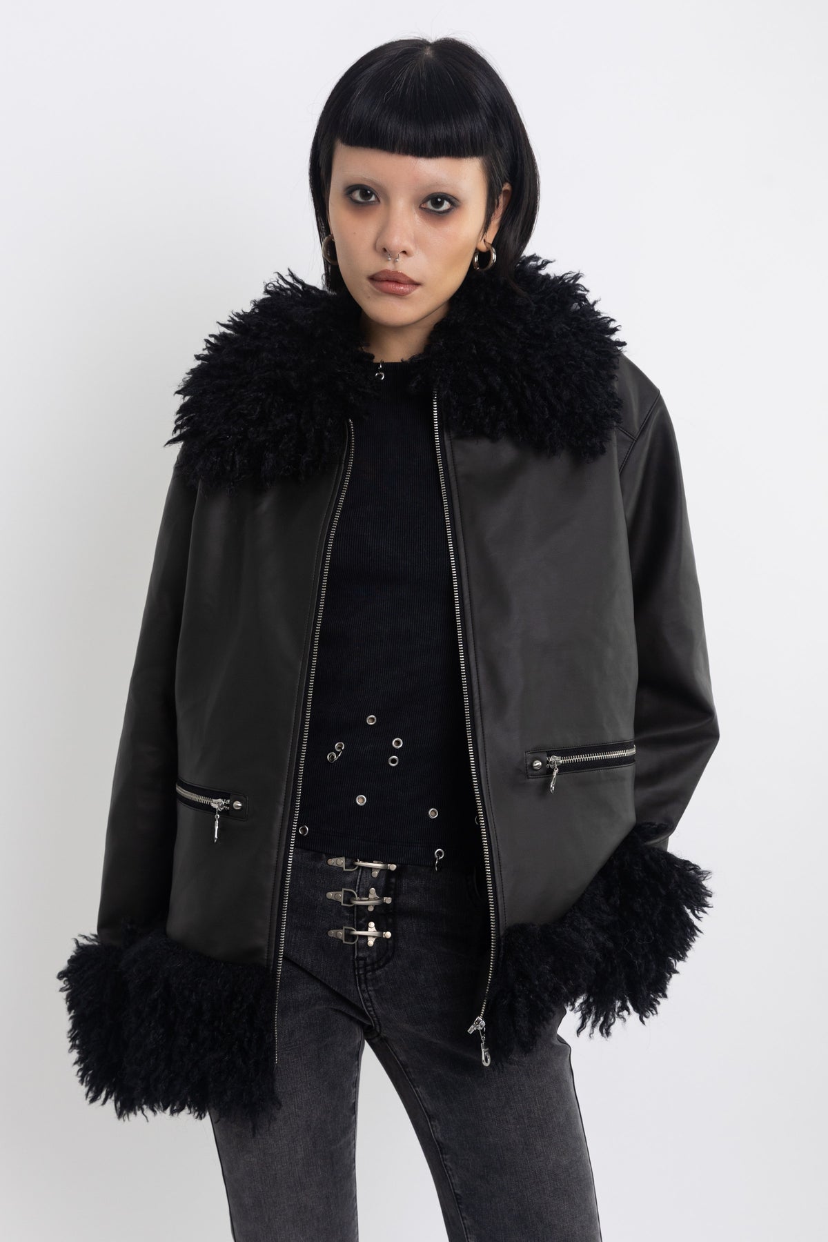 Black faux leather biker jacket with oversized shearling trims and silver hardware, worn by model