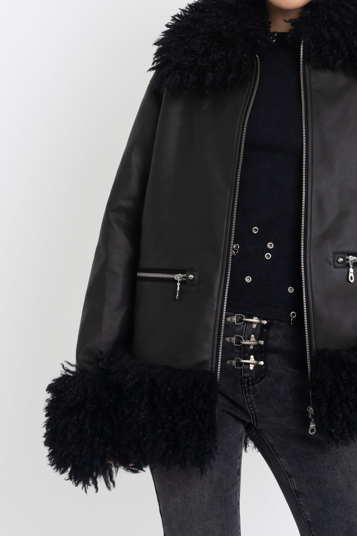 Black faux leather biker jacket with oversized shearling trims and silver hardware, worn by model