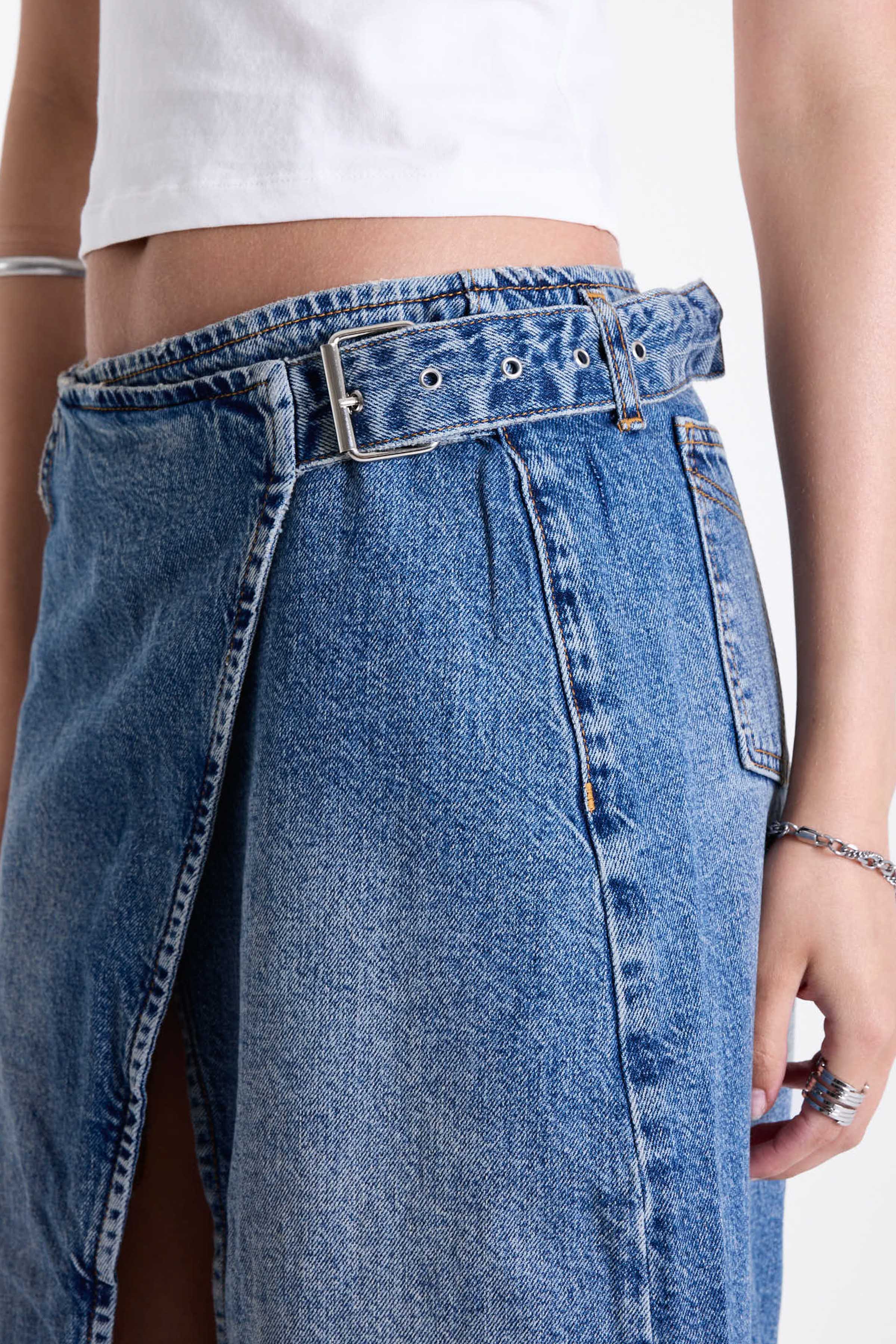 Vintage wash denim maxi skirt with thigh high split and buckle belt fastening, worn by model.