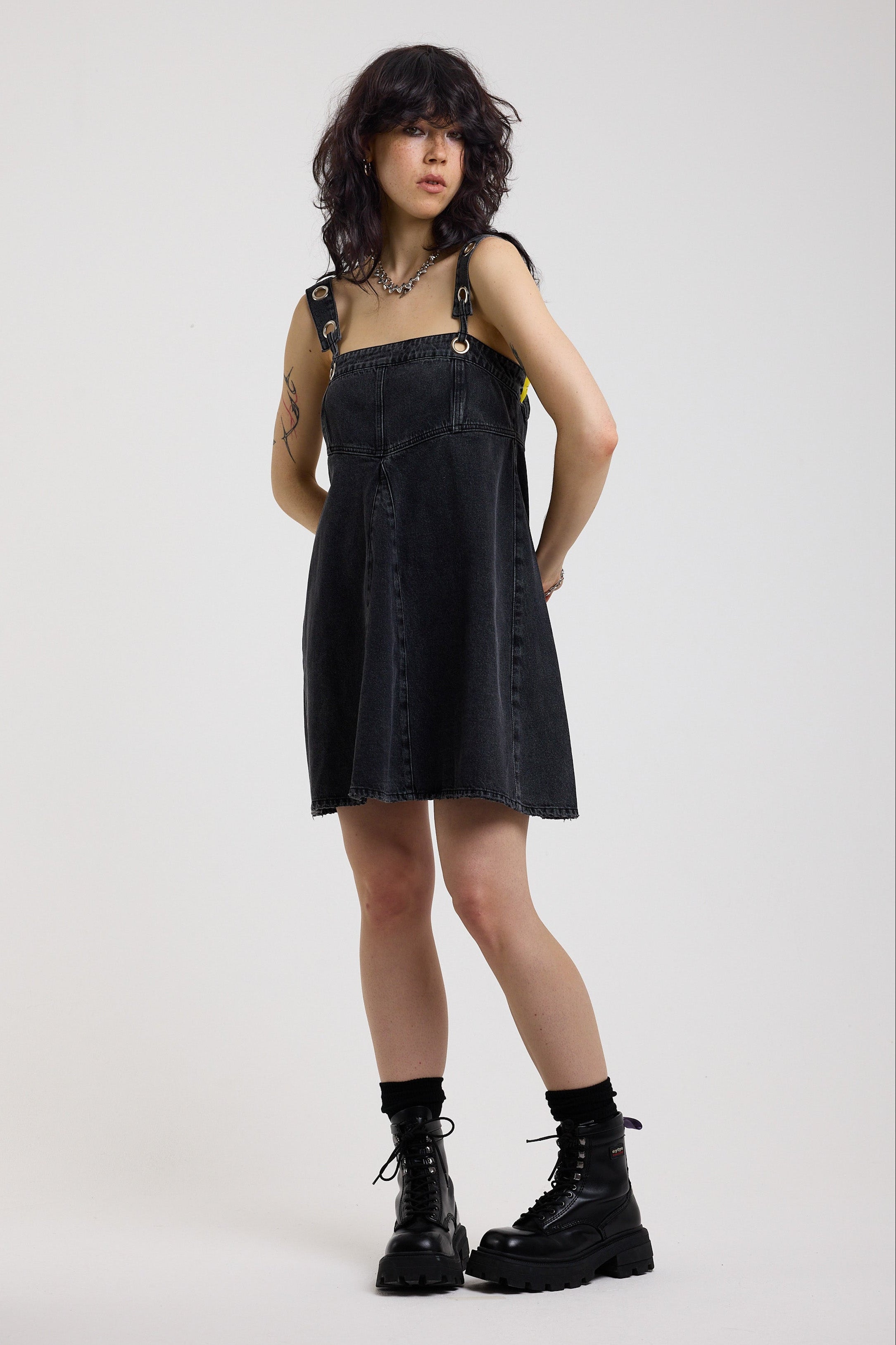 Washed black denim square neck mini dress with eyelet detail straps, worn by model