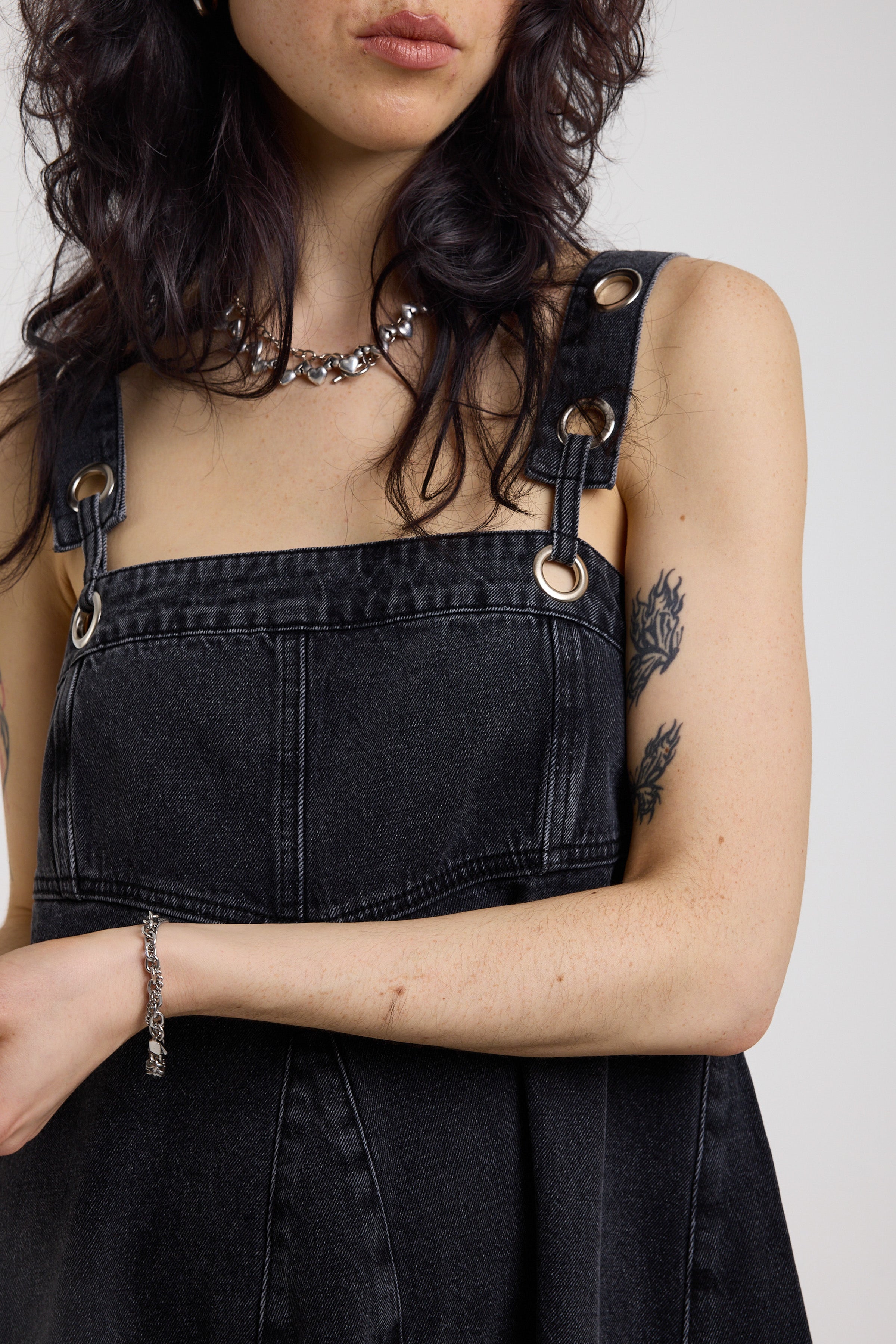 Close up showing eyelet strap detail on washed black denim square neck mini dress, worn by model