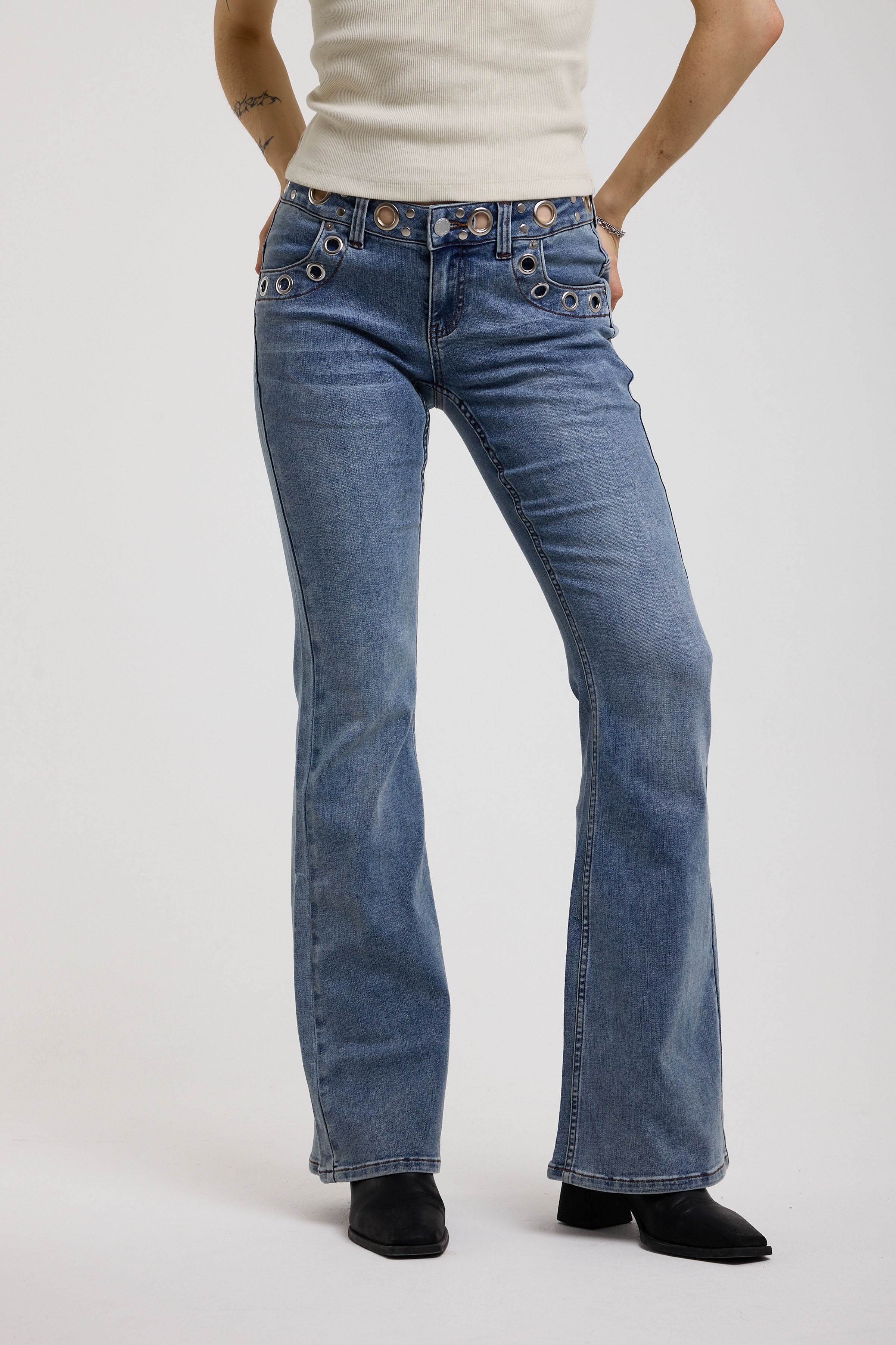 Blue flare bootcut jeans with eyelet cut out detail, worn by model