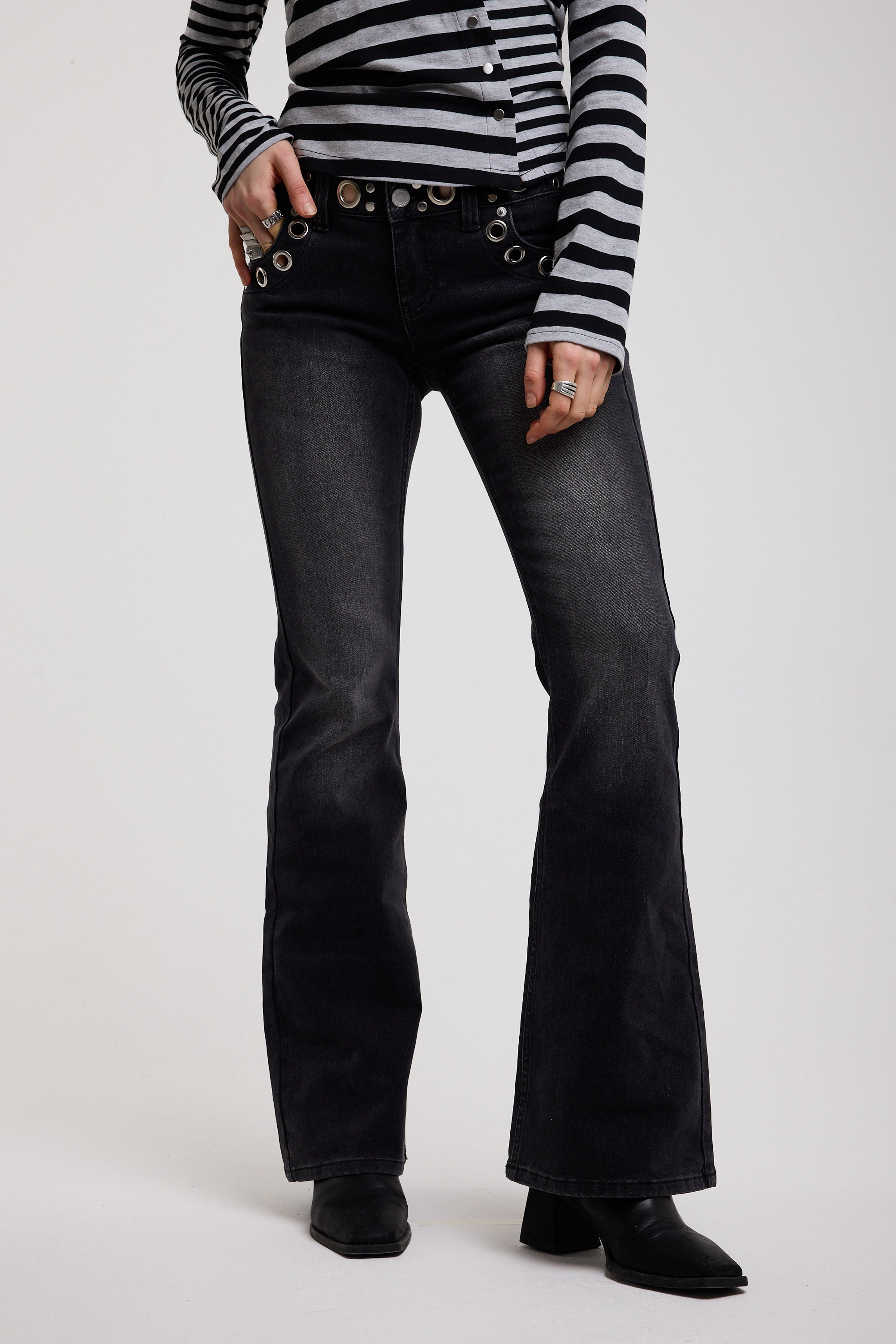 Washed black flare bootcut jeans with eyelet cut out detail, worn by model