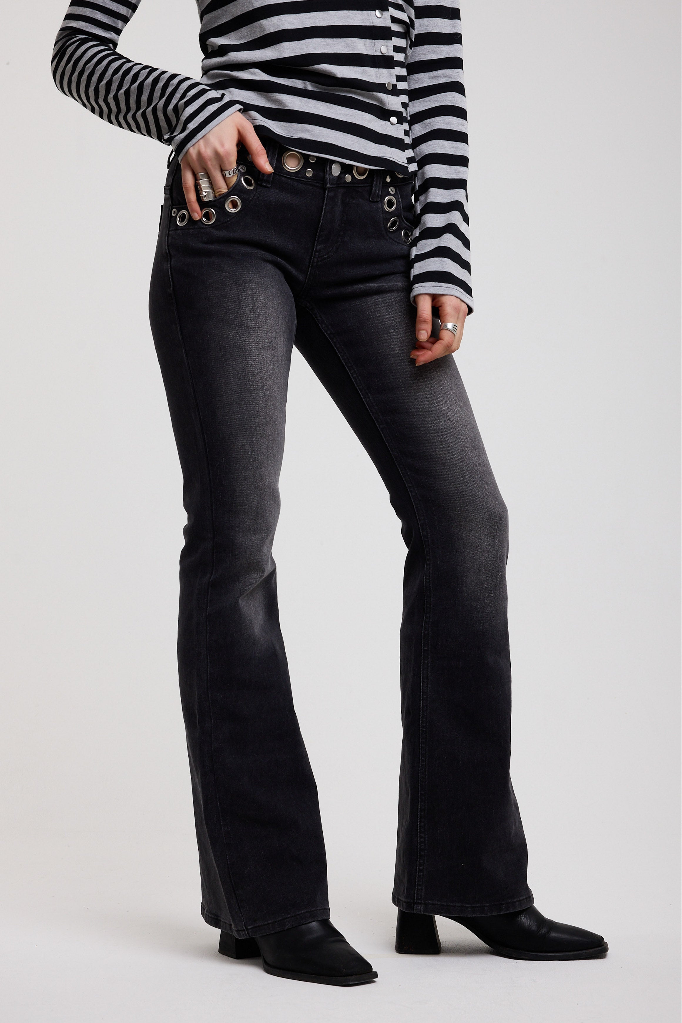 Washed black flare bootcut jeans with eyelet cut out detail, worn by model