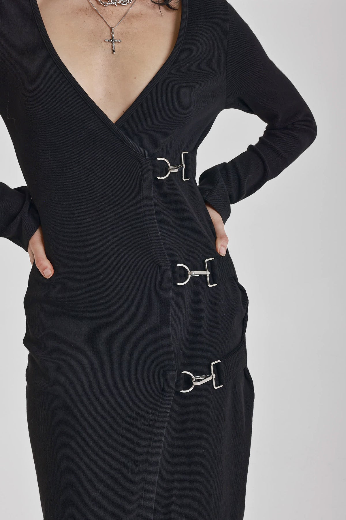 Black wrap front midi dress with silver trigger clasps and long sleeves, worn by model