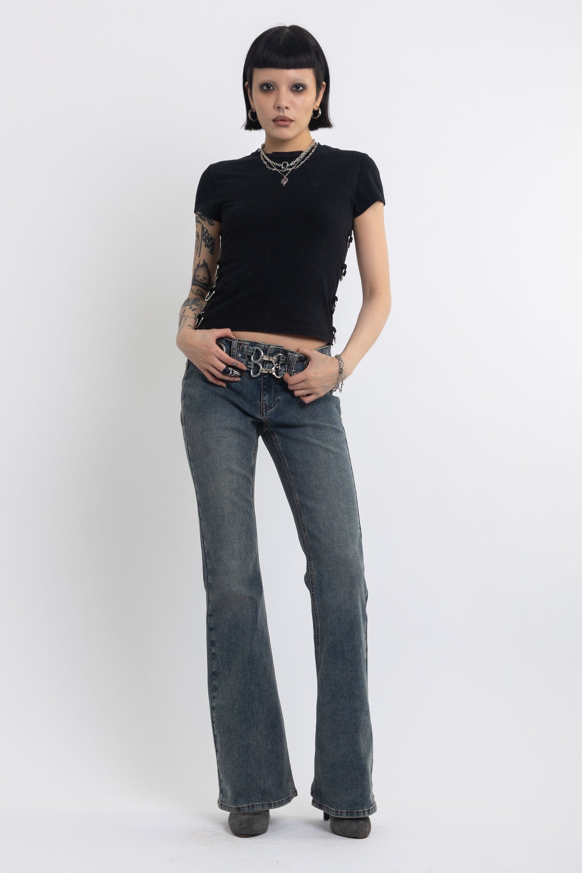 Vintage wash low rise flare jeans with eyelet and horsebit clasp belt, worn by model