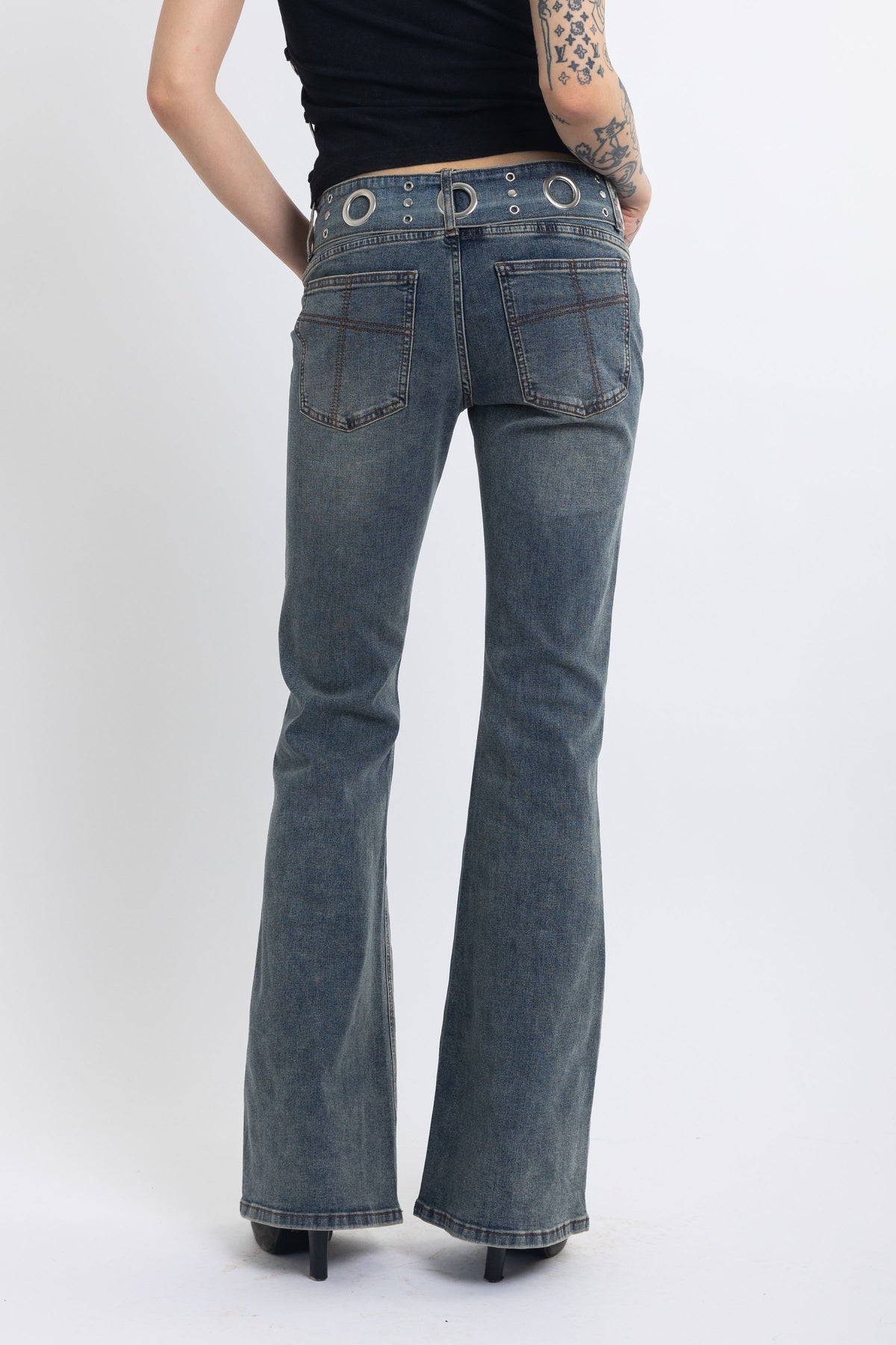 Vintage wash low rise flare jeans with eyelet and horsebit clasp belt, worn by model