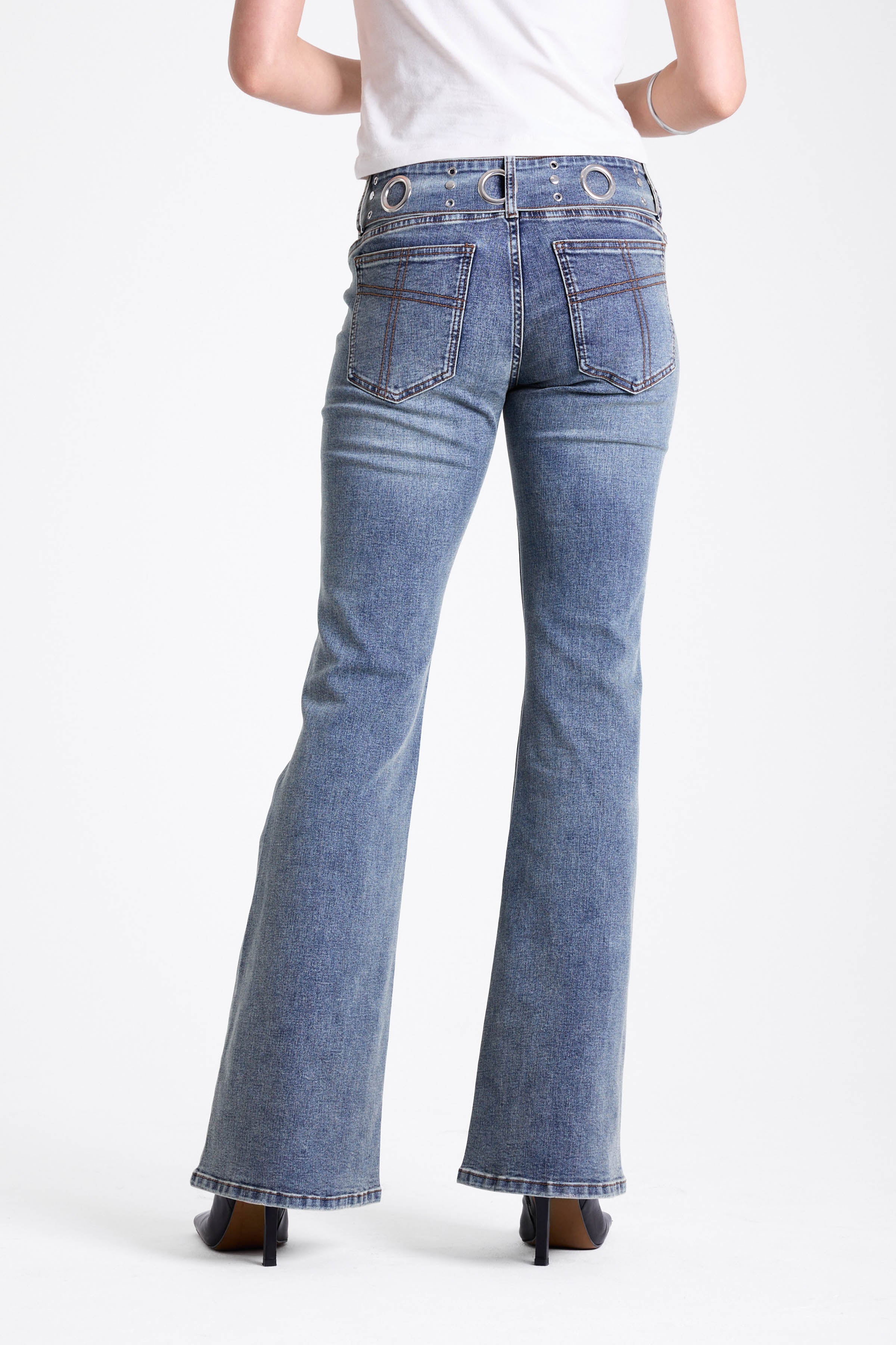 Vintage wash low rise flare jeans with oversized eyelet buckle belt, worn by mdoel