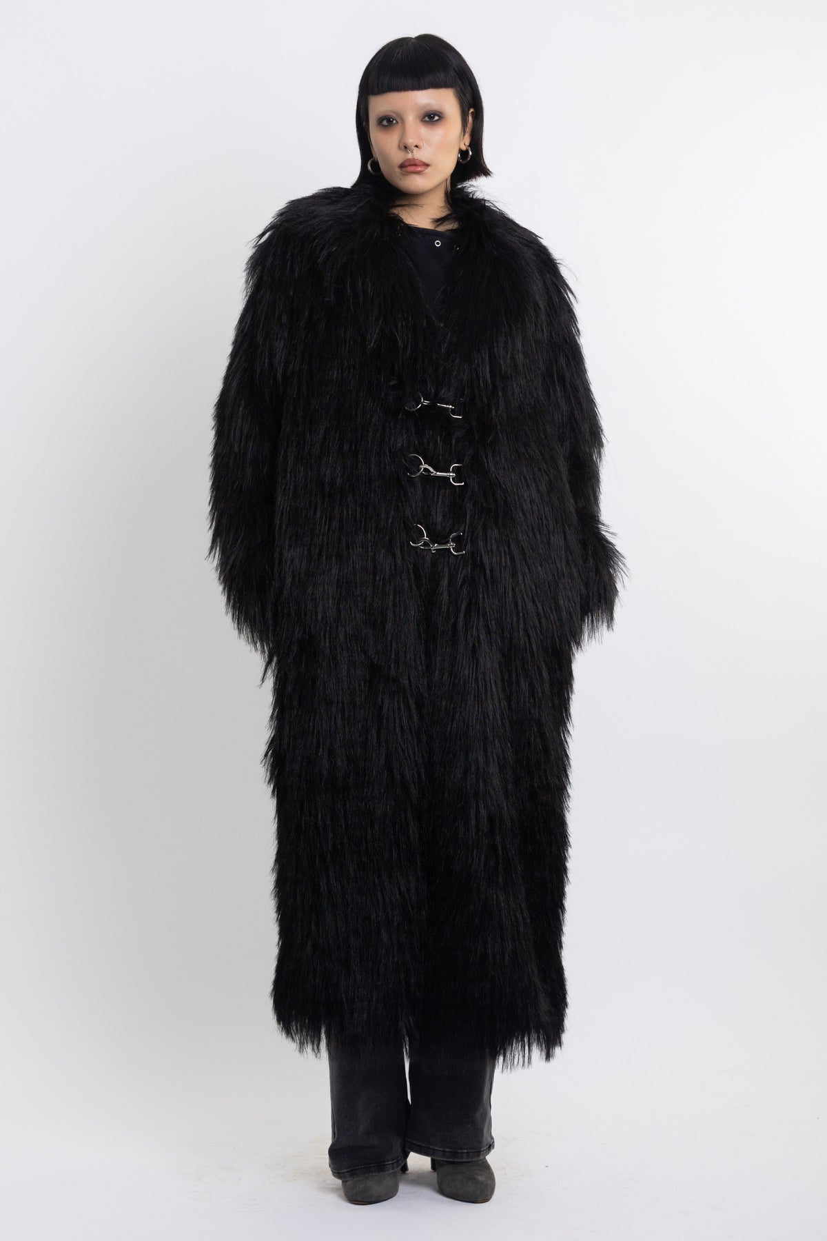 Longline black shaggy faux fur coat with silver horsebit clasps and shawl collar, worn by model