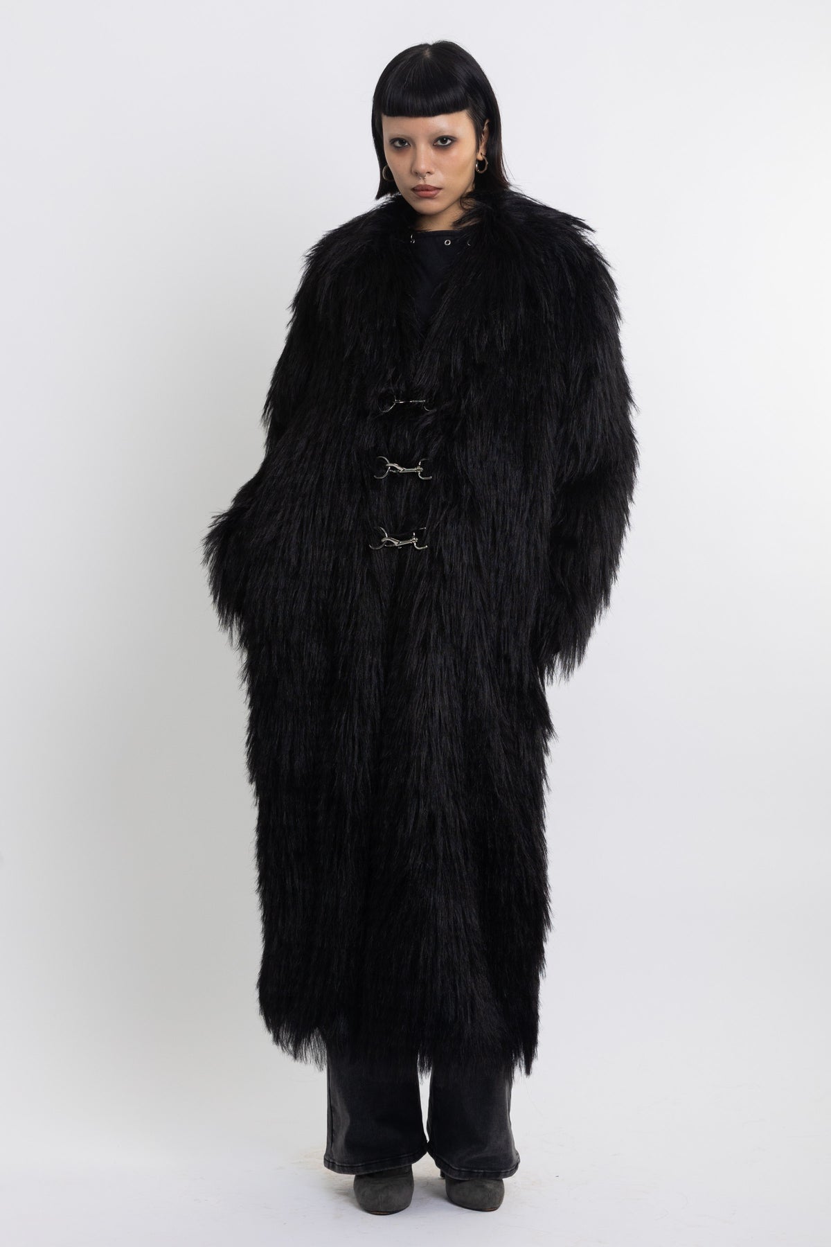 Longline black shaggy faux fur coat with silver horsebit clasps and shawl collar, worn by model