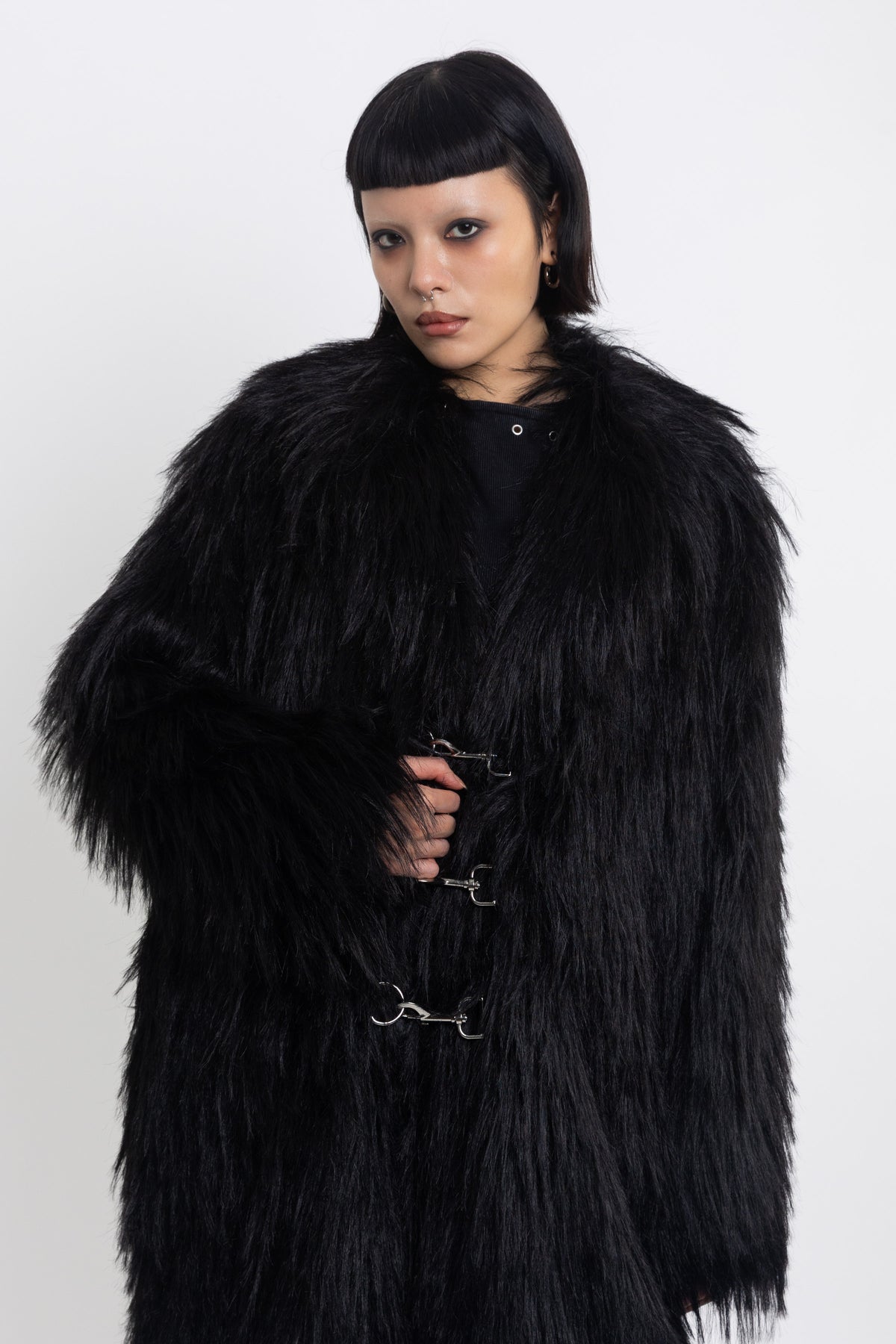 Longline black shaggy faux fur coat with silver horsebit clasps and shawl collar, worn by model