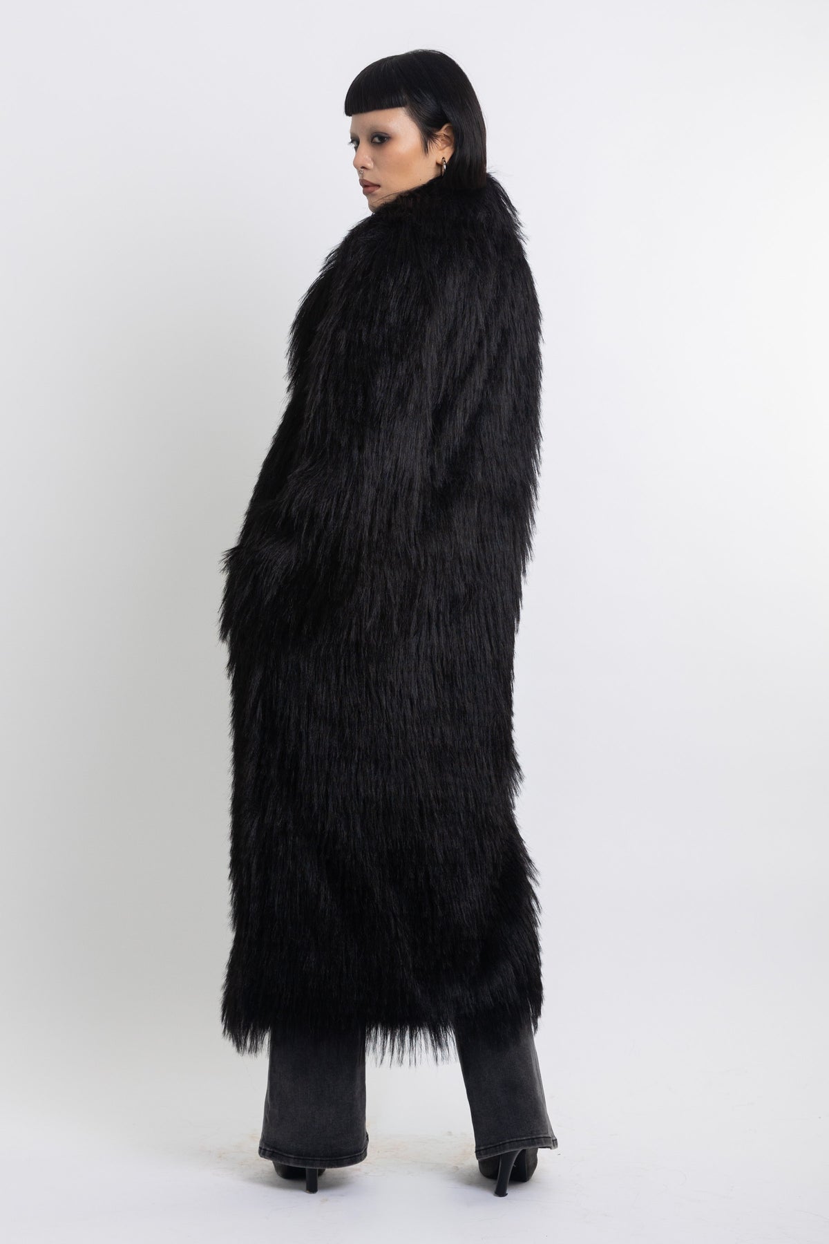 Longline black shaggy faux fur coat with silver horsebit clasps and shawl collar, worn by model
