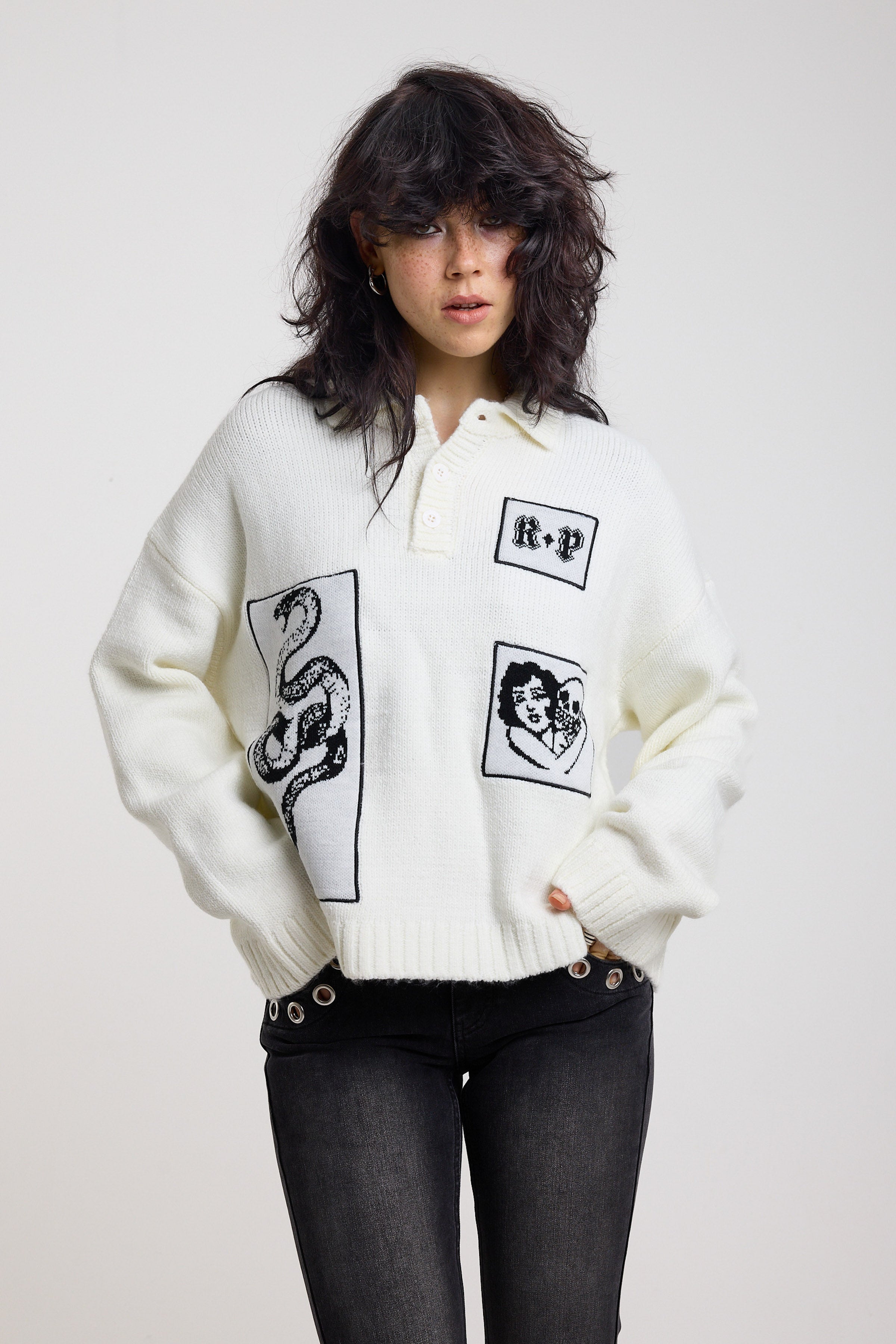 Cream oversized knit jumper with black graphic patch details and polo collar, worn by model