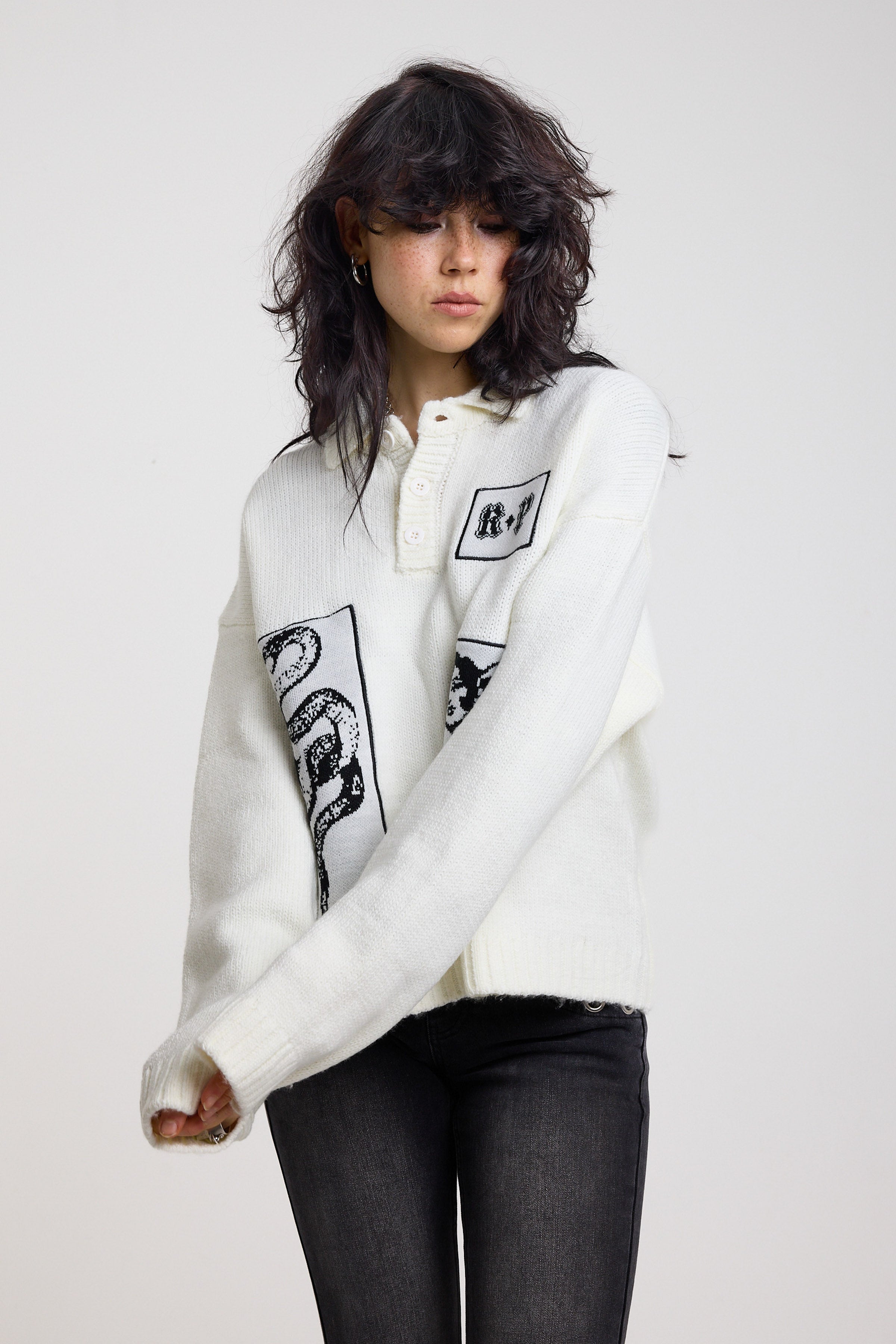 Cream oversized knit jumper with black graphic patch details and polo collar, worn by model