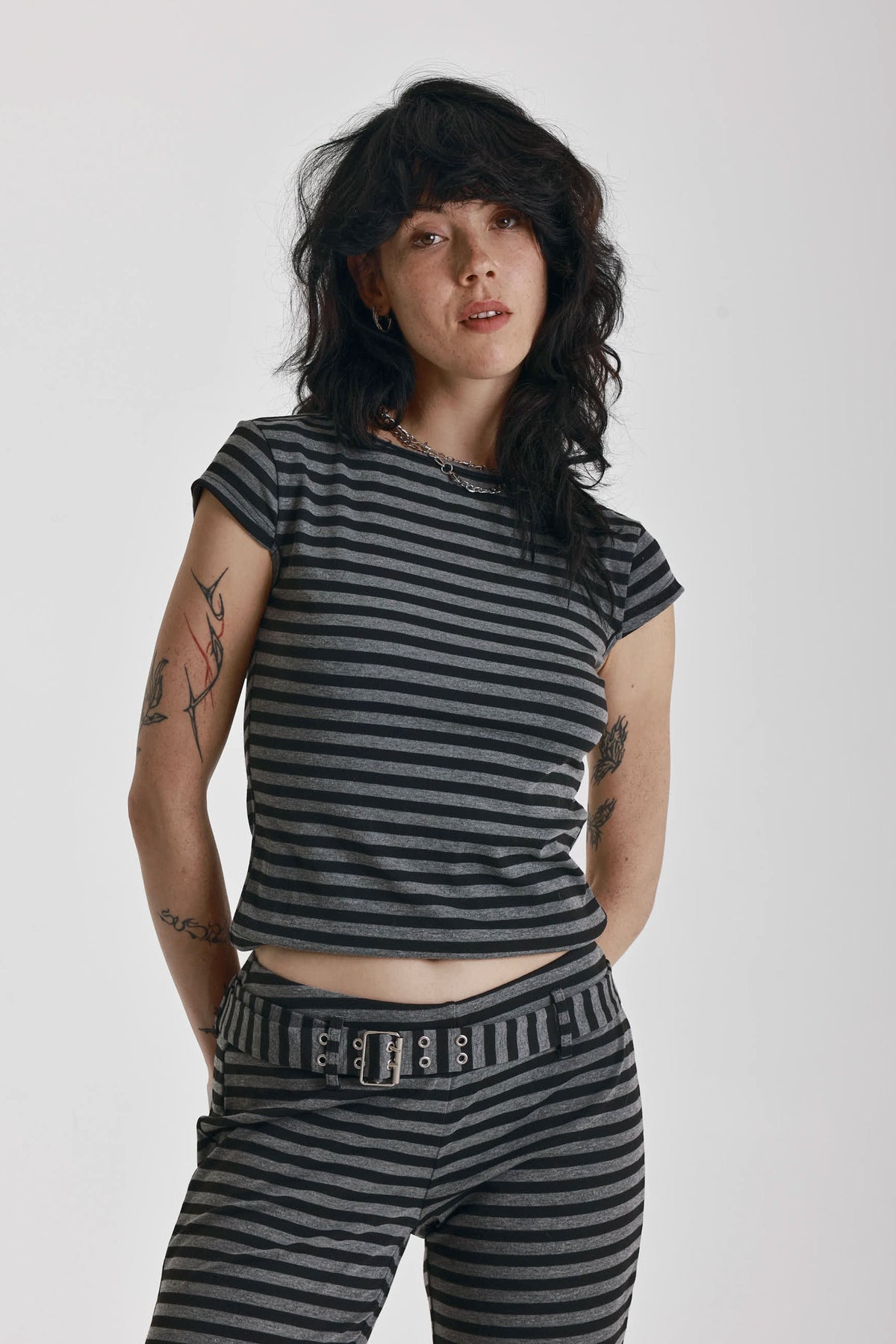 Grey and black stripe cap sleeve t-shirt with open back and eyelet buckle straps, worn by model