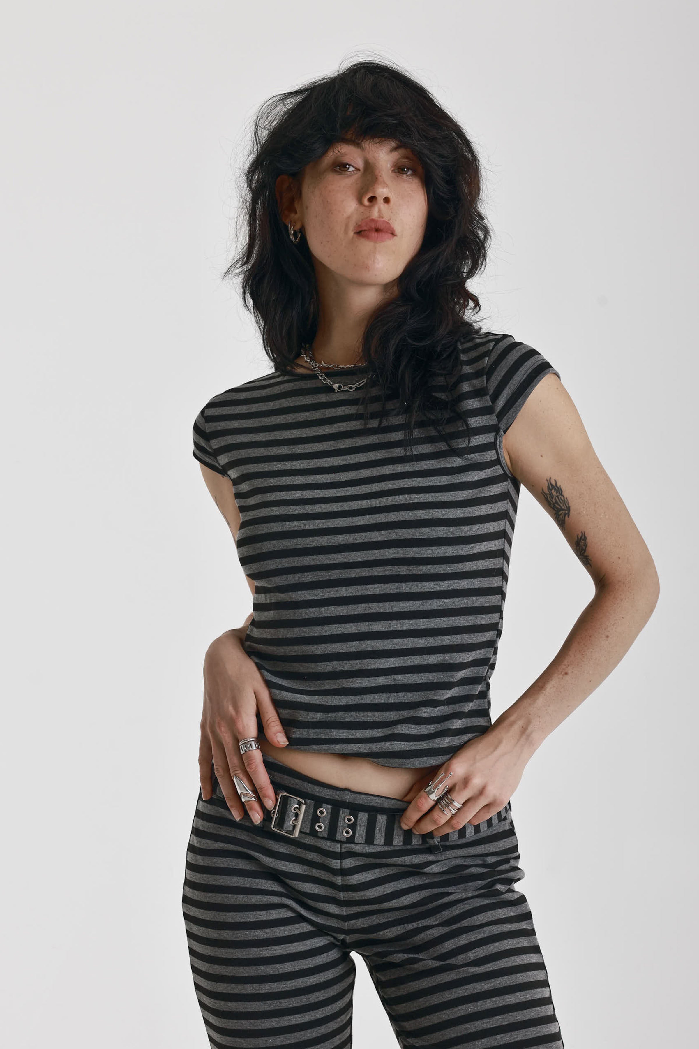 Grey and black stripe cap sleeve t-shirt with open back and eyelet buckle straps, worn by model