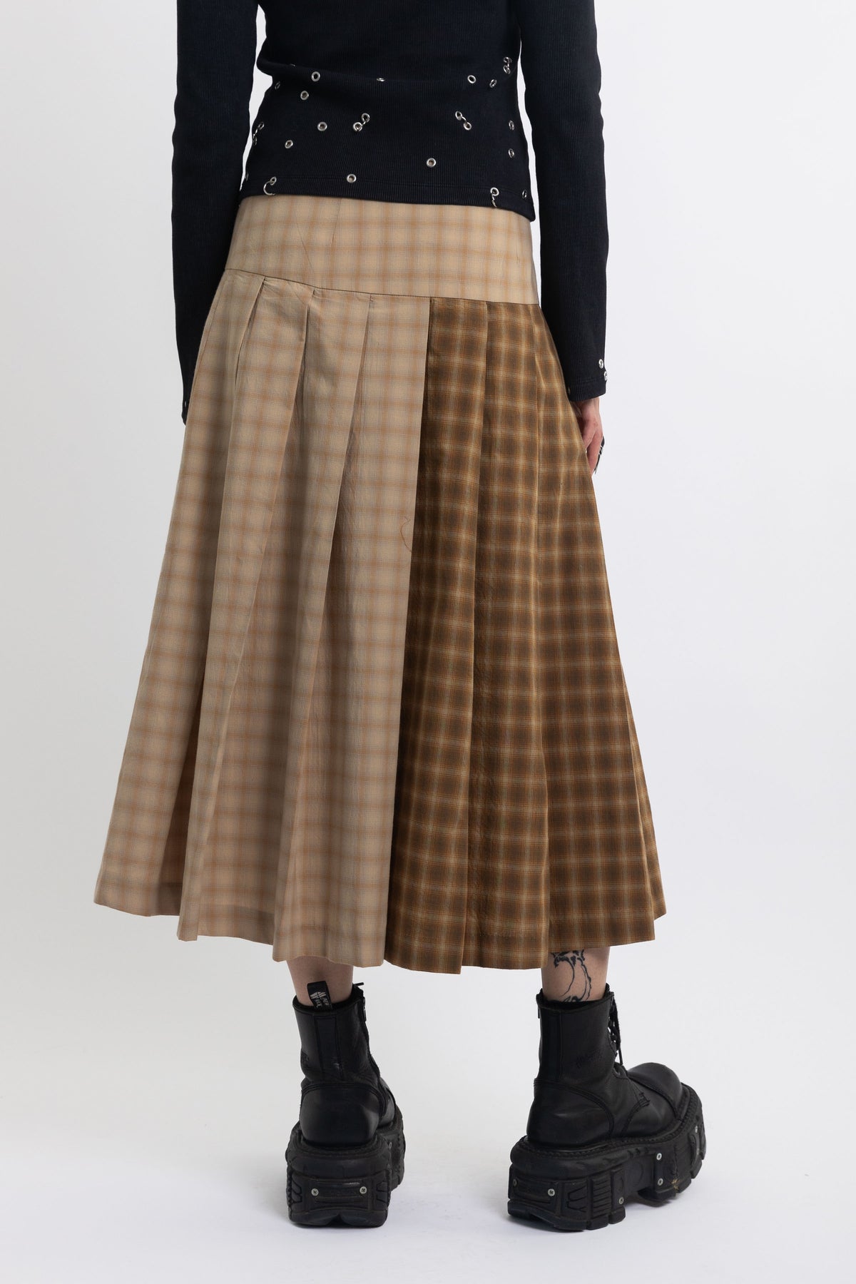 Spliced check pleated kilt midi skirt with silver clasp detail and thigh high split, worn by model