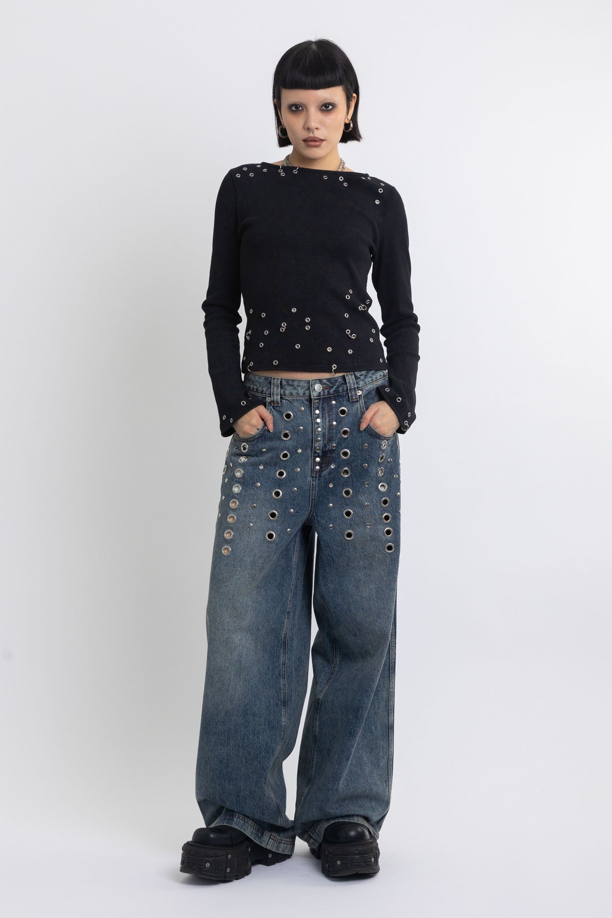 Mid blue wash ultra baggy colossus jeans with silver stud and eyelet hardware, worn by model