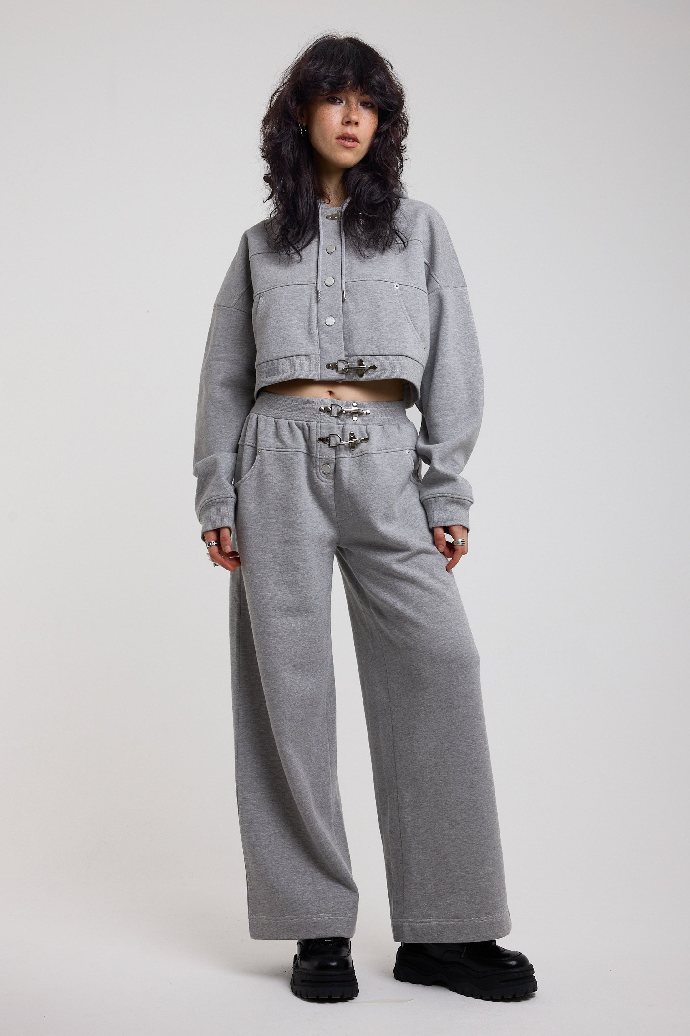 Grey wide leg trackpants with silver hardware clasp detail, worn by model