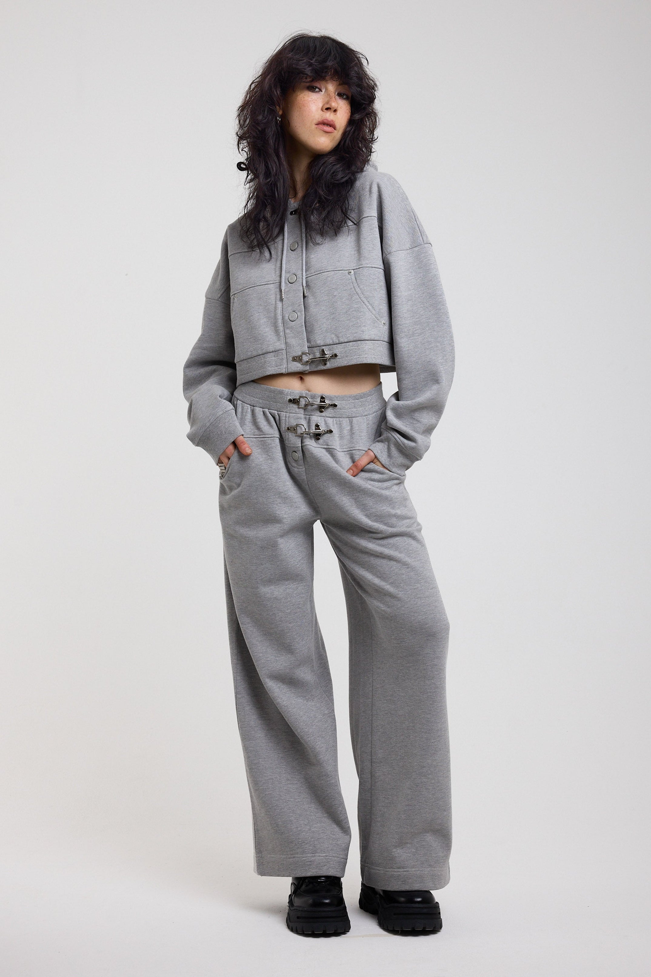 Grey wide leg trackpants with silver hardware clasp detail, worn by model