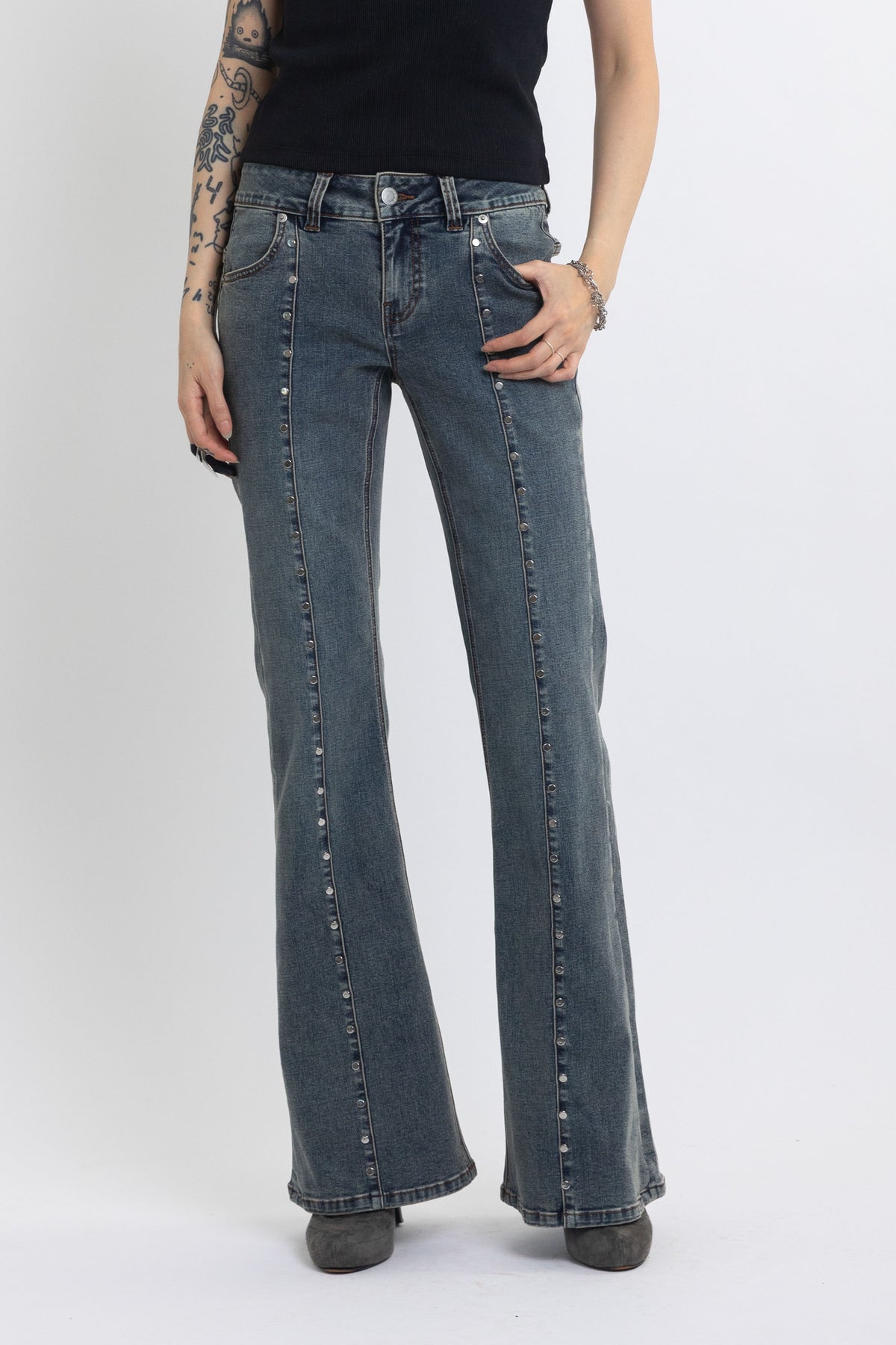 Washed denim low rise flare jeans with silver stud and front seam detail, worn by model