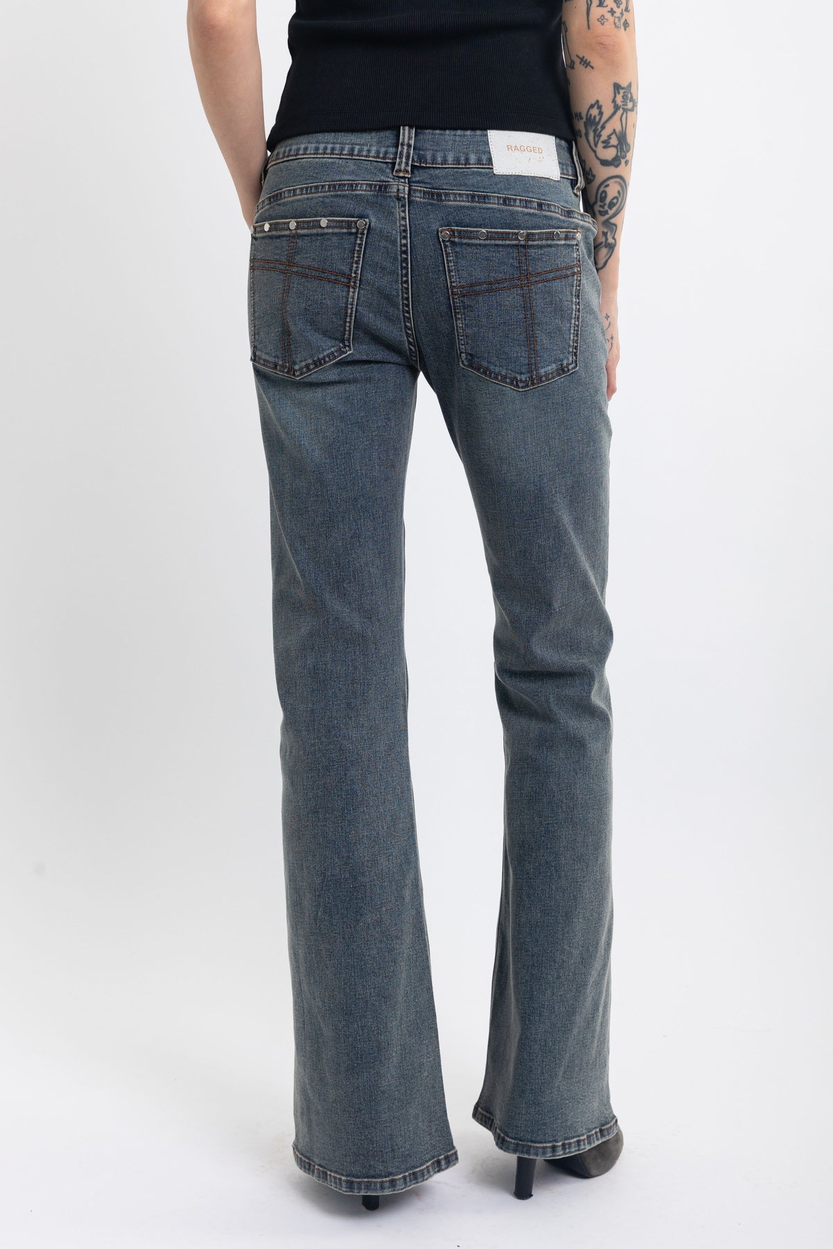 Washed denim low rise flare jeans with silver stud and front seam detail, worn by model