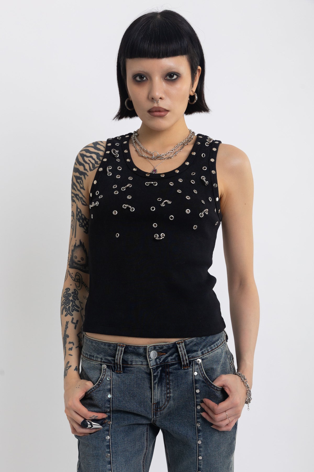 Black tank top with silver eyelets and stud hardware, worn by model
