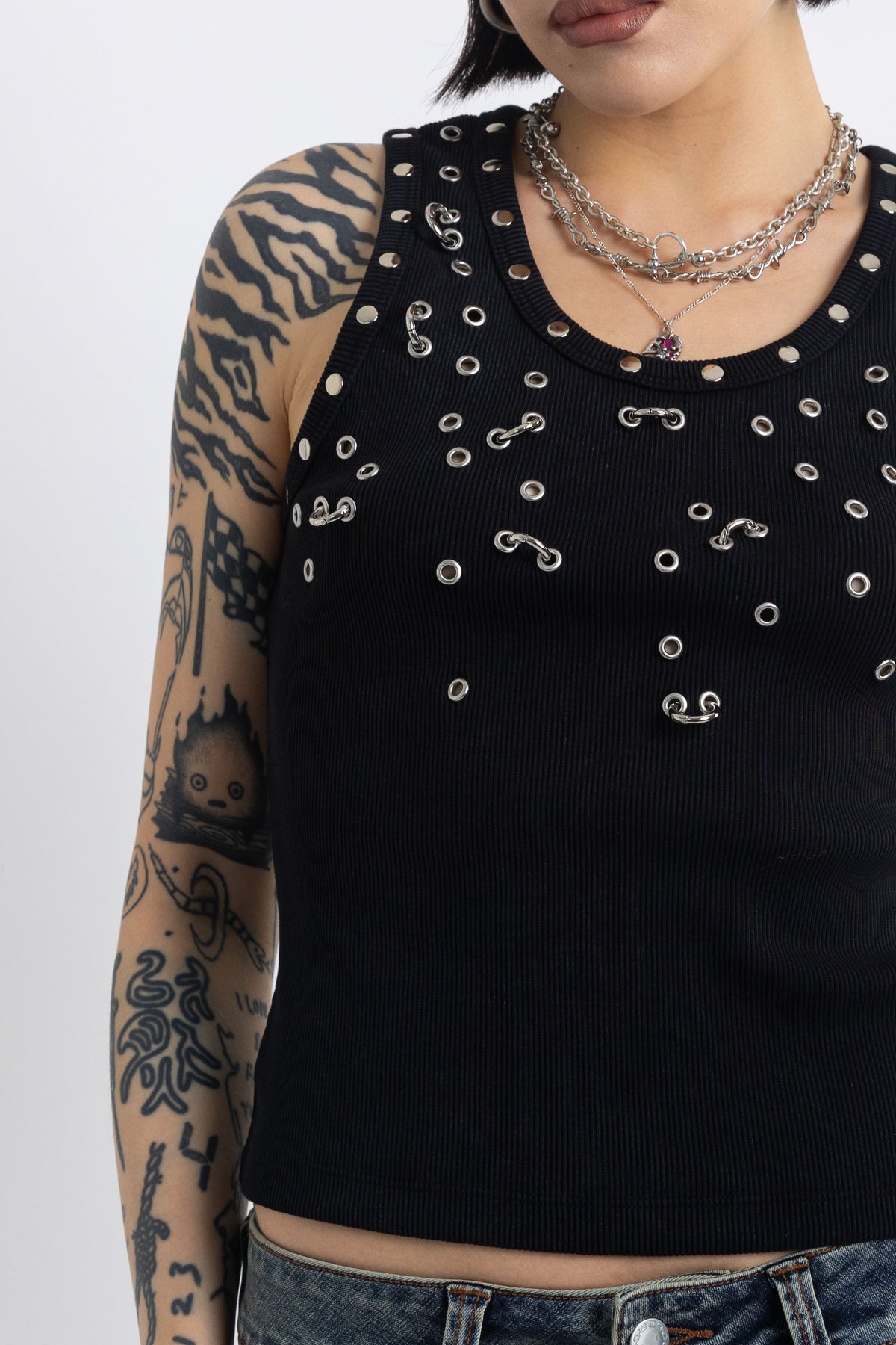 Black tank top with silver eyelets and stud hardware, worn by model