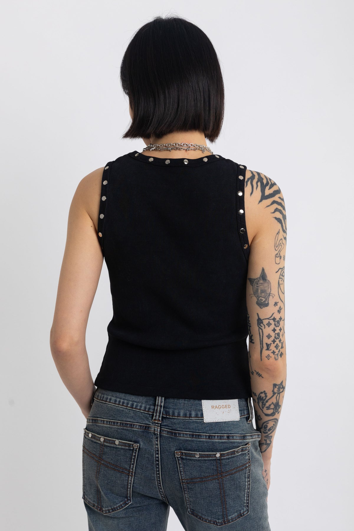 Black tank top with silver eyelets and stud hardware, worn by model