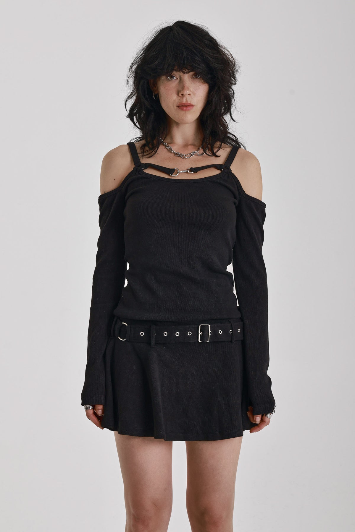 Washed black long-sleeve cold-shoulder mini dress with trigger clasp strap and eyelet belt, worn by model