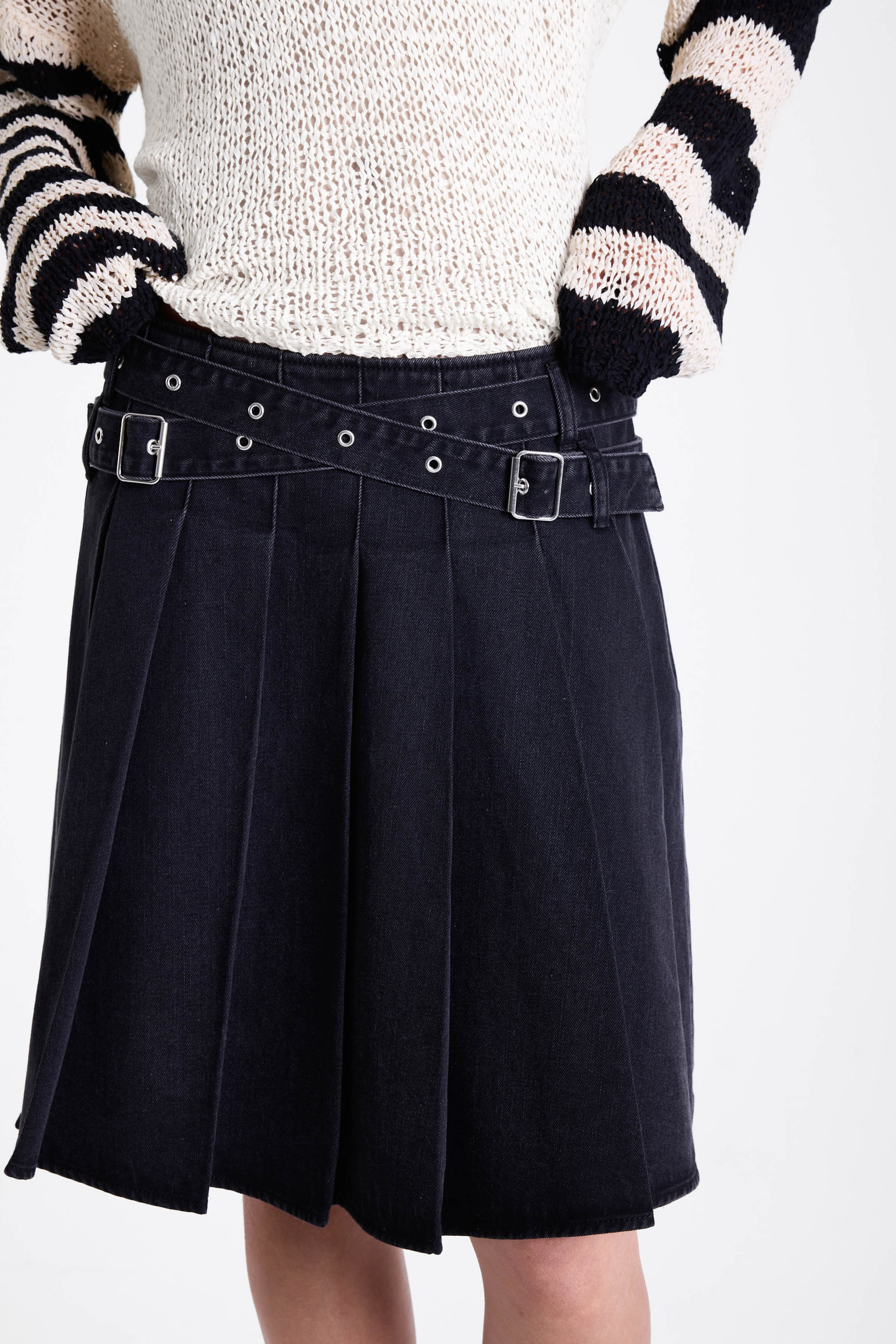 Washed denim pleated midi skirt with double eyelet crossover belt detail, worn by model
