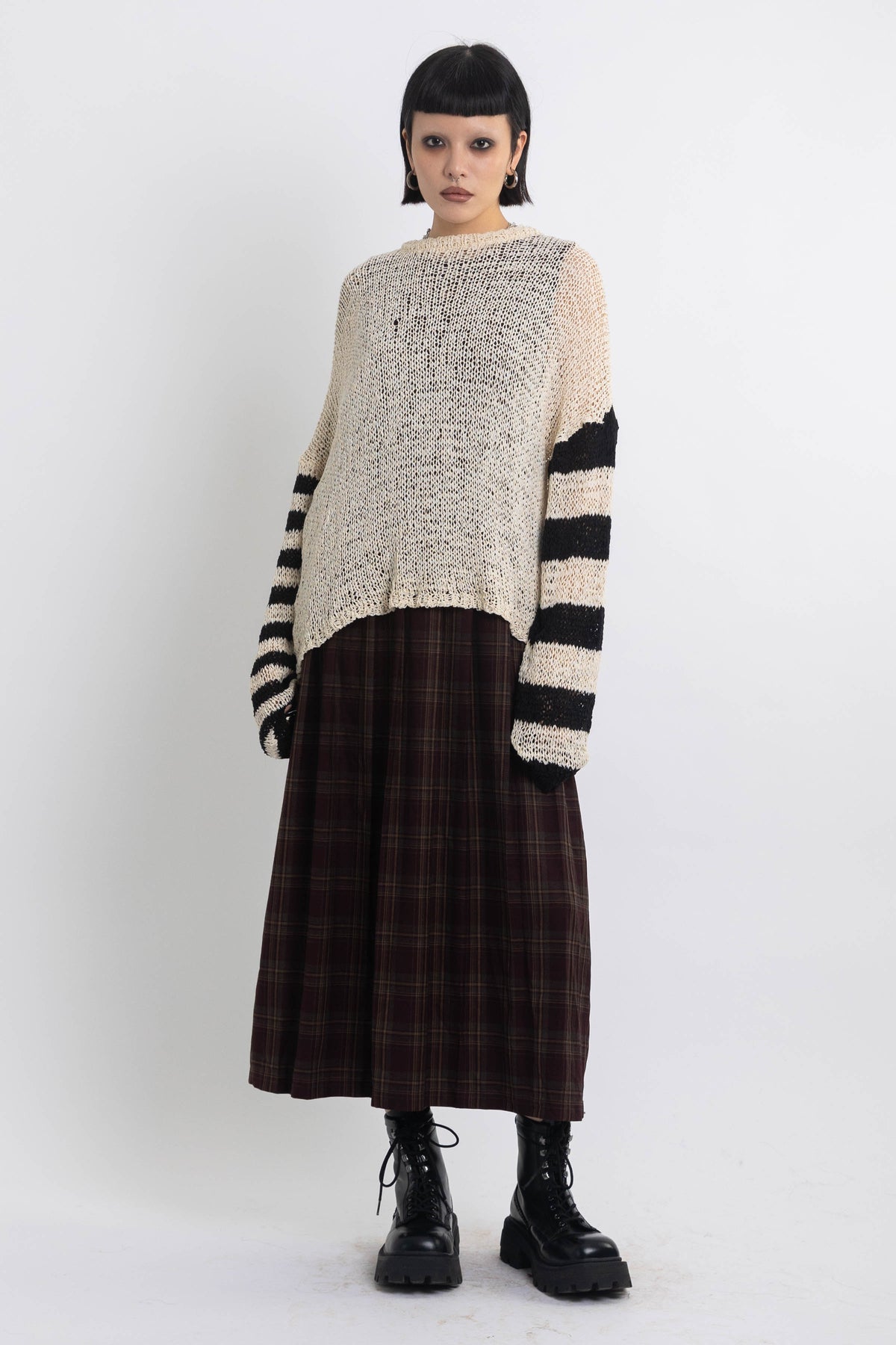 Ecru open knit jumper with asymmetric black stripe sleeves, worn by model