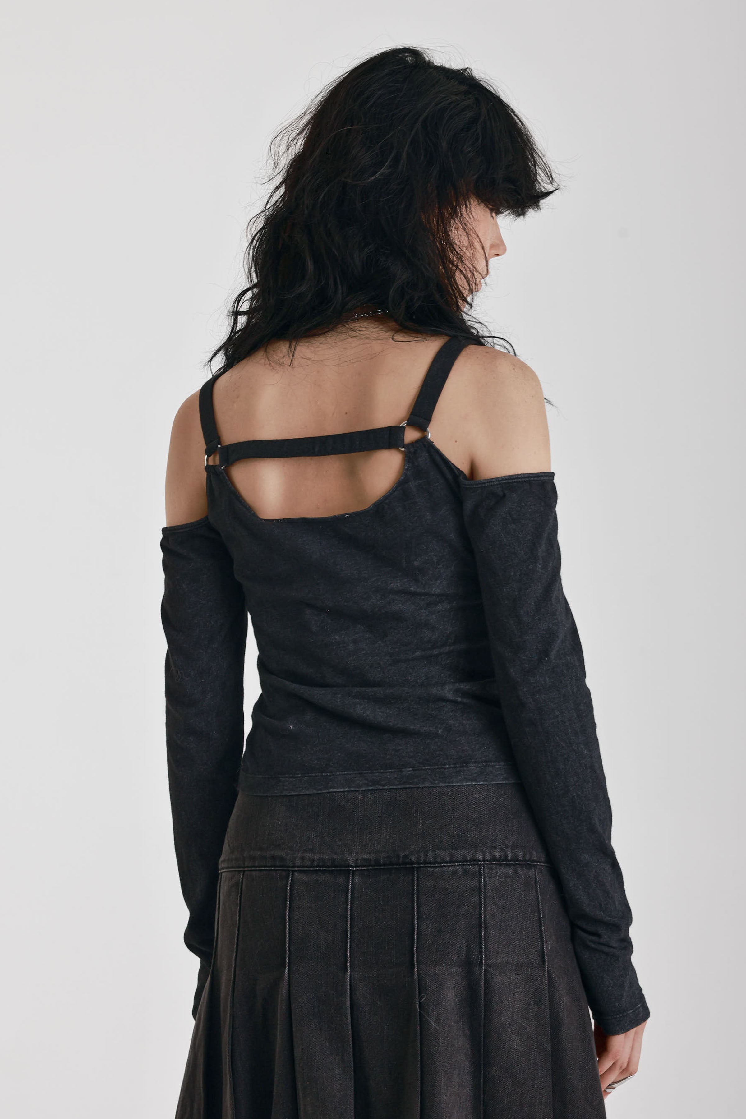 Washed black long-sleeve cold-shoulder top with cutout eyelet straps and silver buckles, worn by model