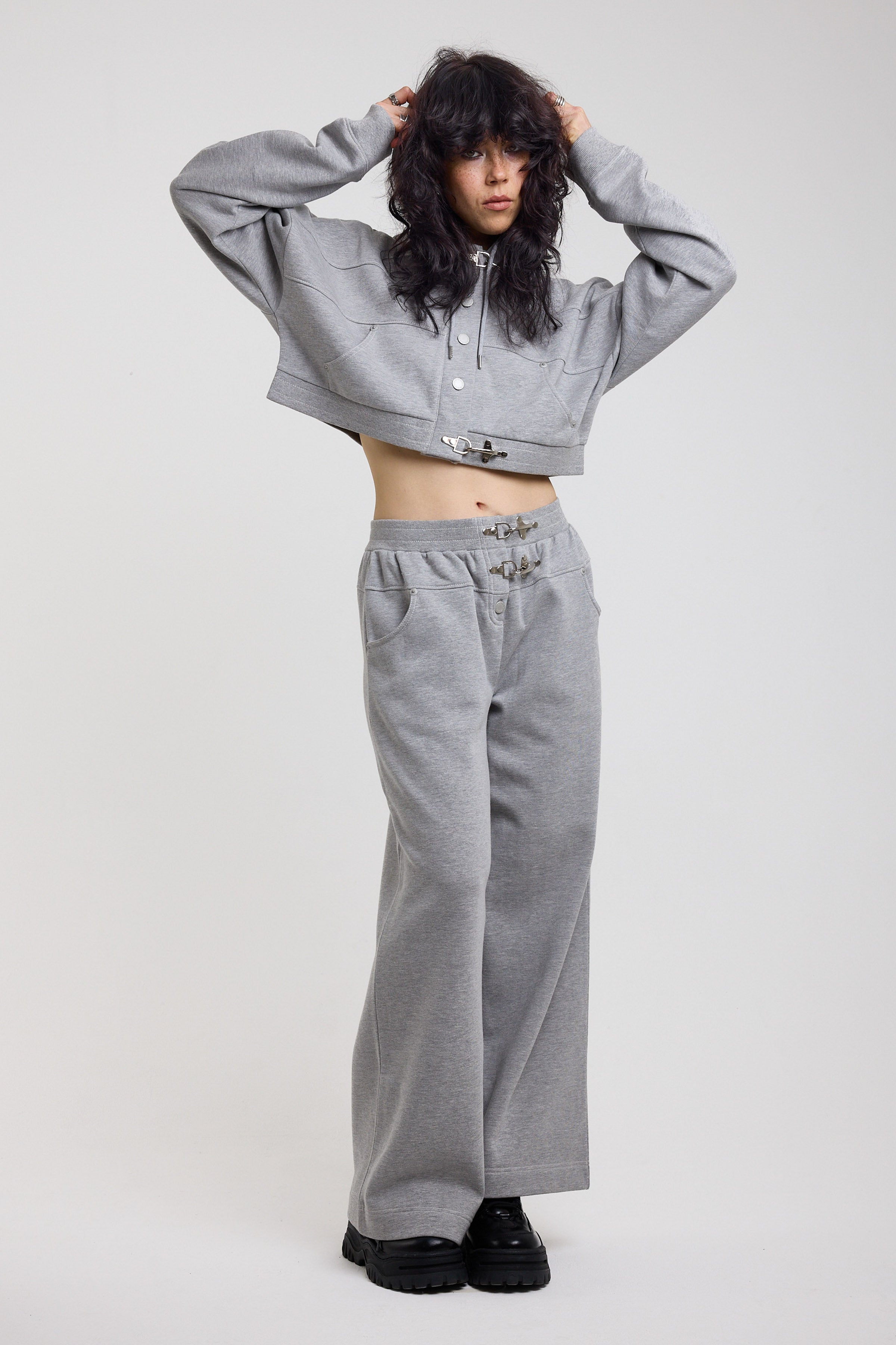 Grey cropped hoodie with silver hardware clasps worn as a tracksuit set by model