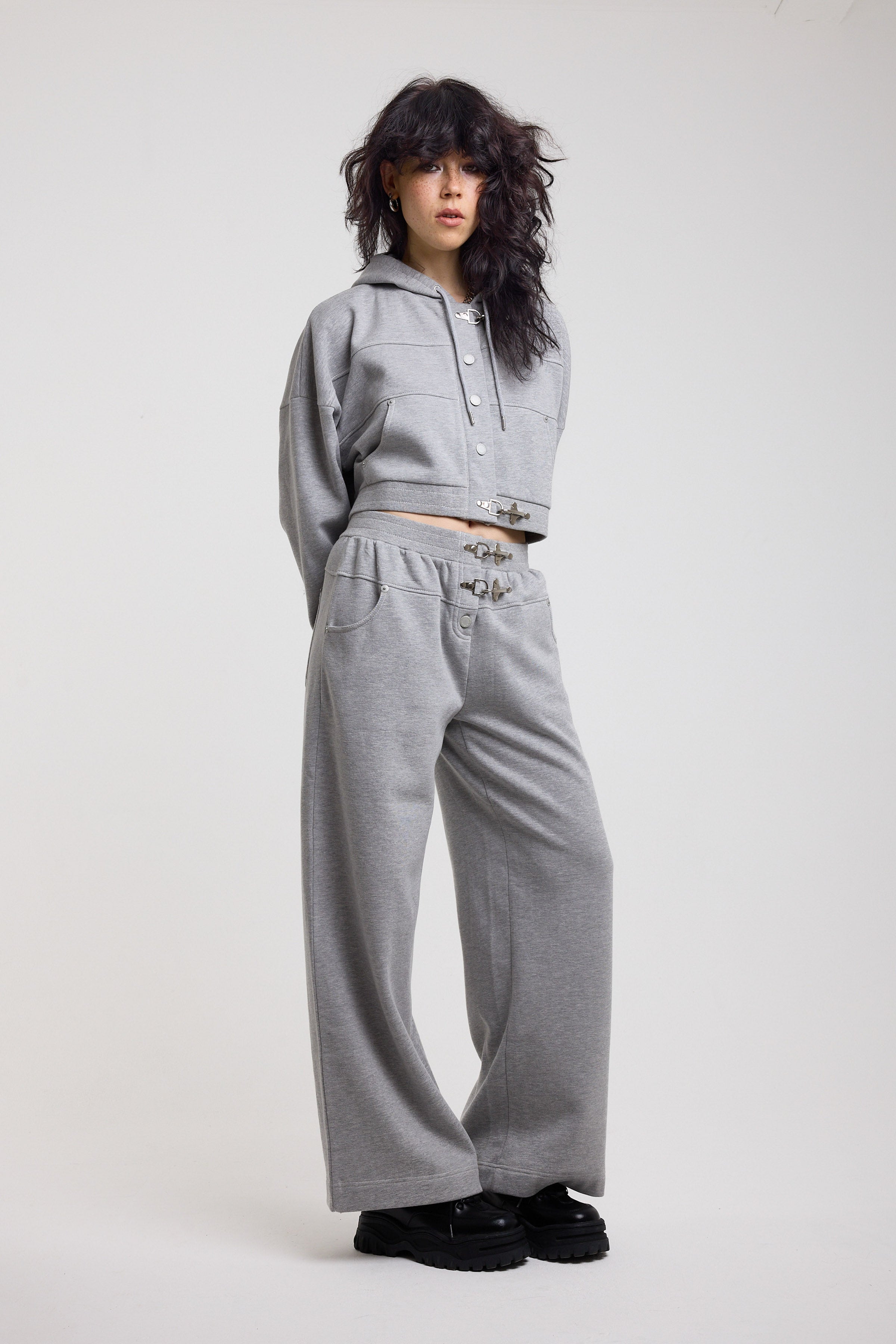 Grey cropped hoodie with silver hardware clasps, worn by model