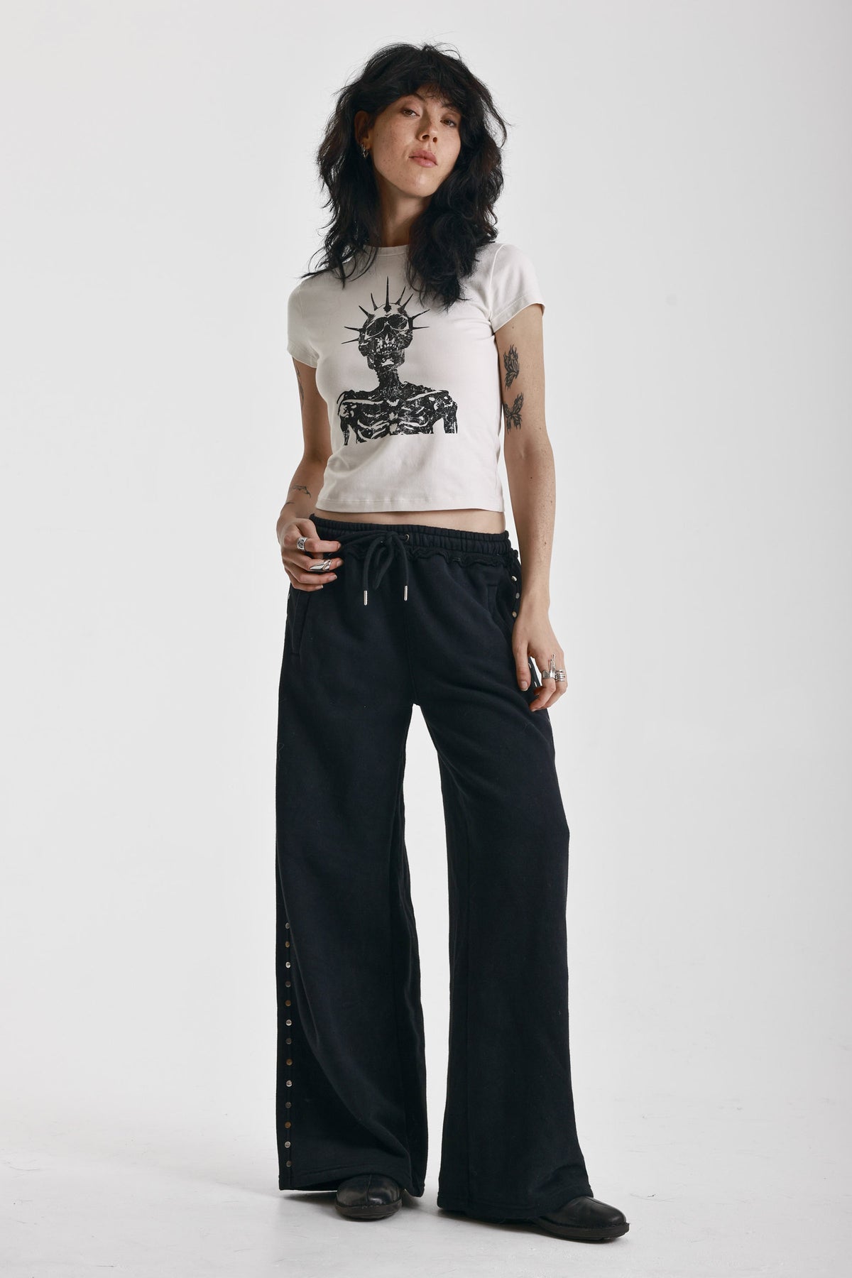 Ecru baby tee with black skeleton skull graphic print, worn by model