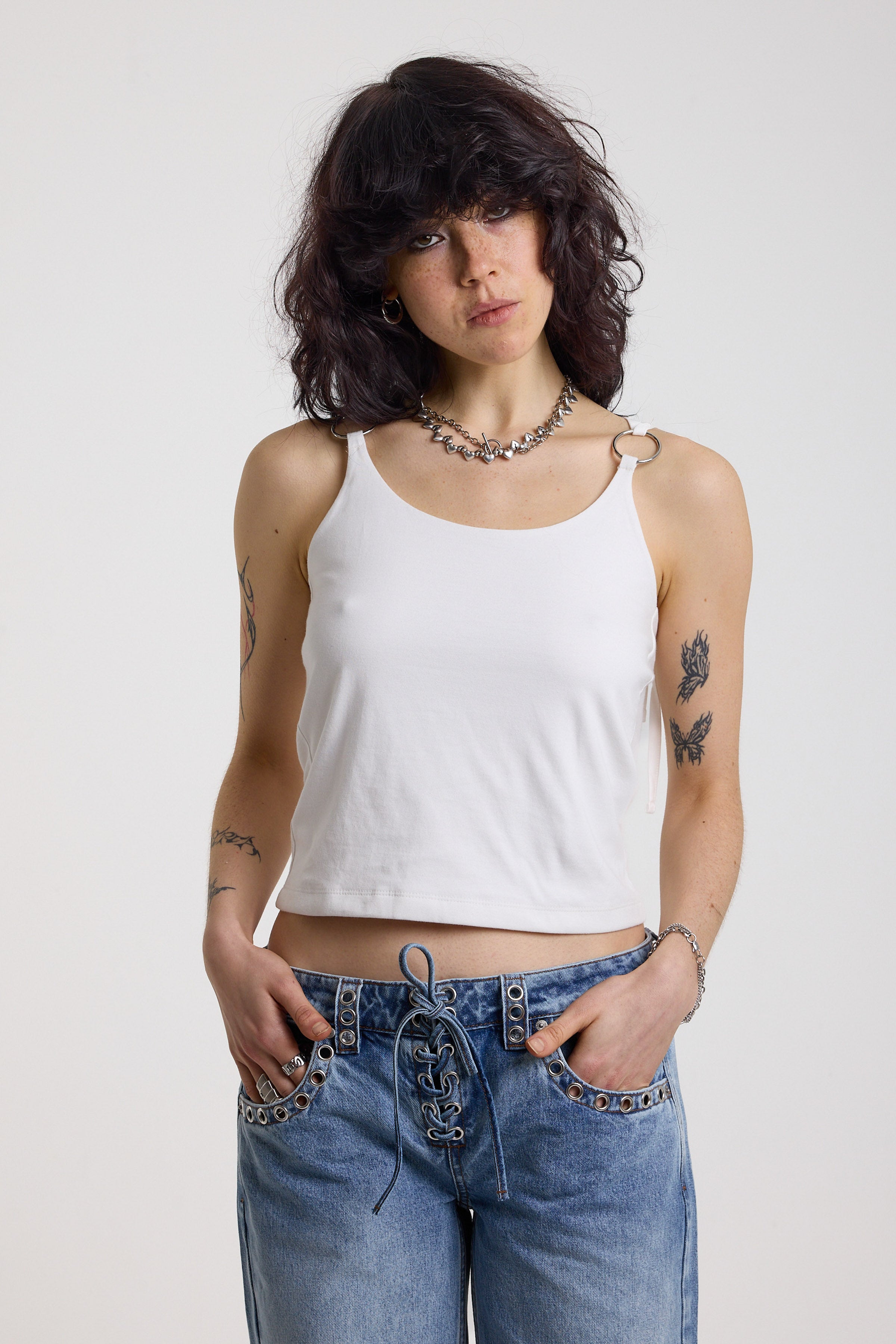 White strappy cami top with tie straps, cowl back and silver O rings, worn by model