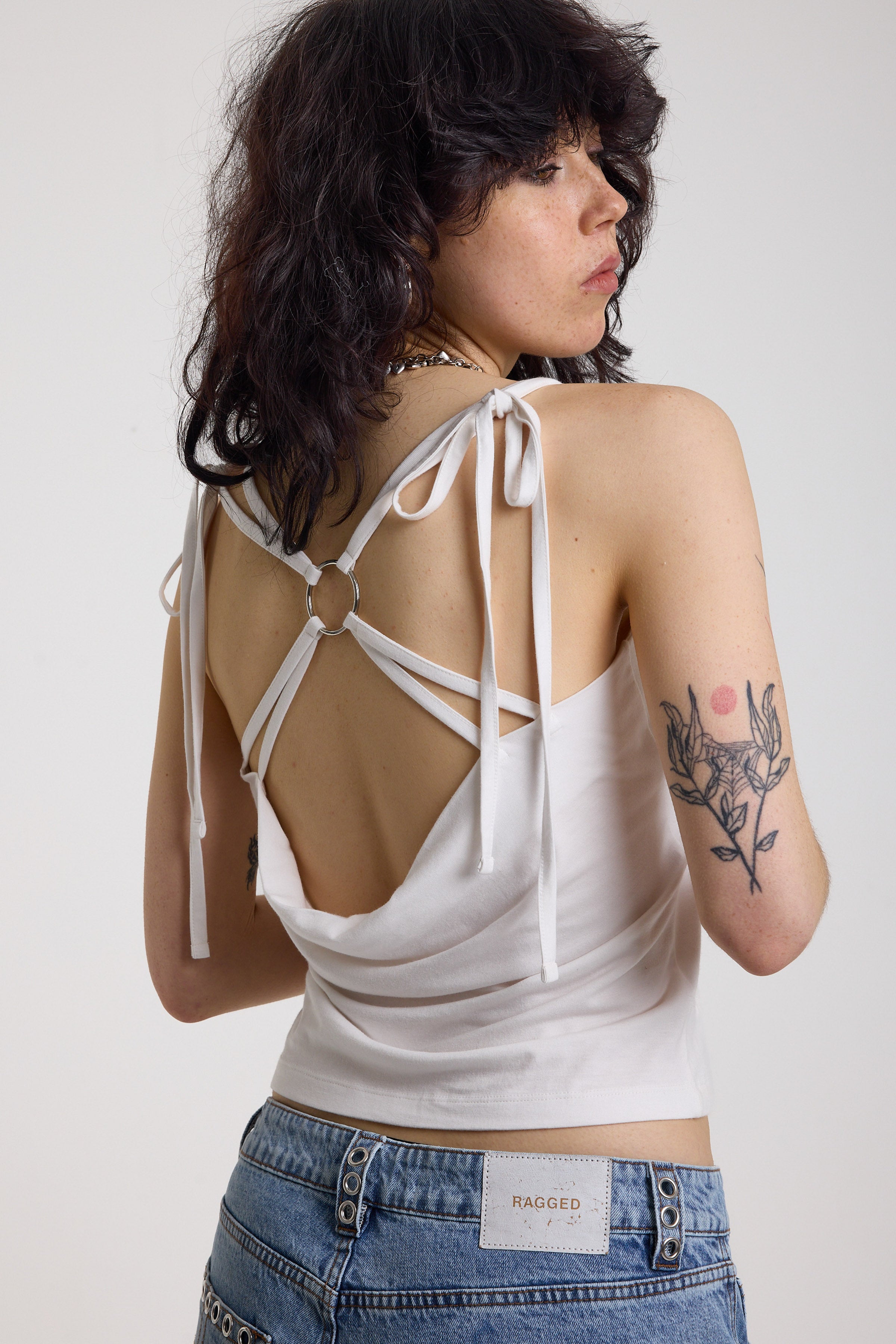 White strappy cami top with tie straps, cowl back and silver O rings, worn by model