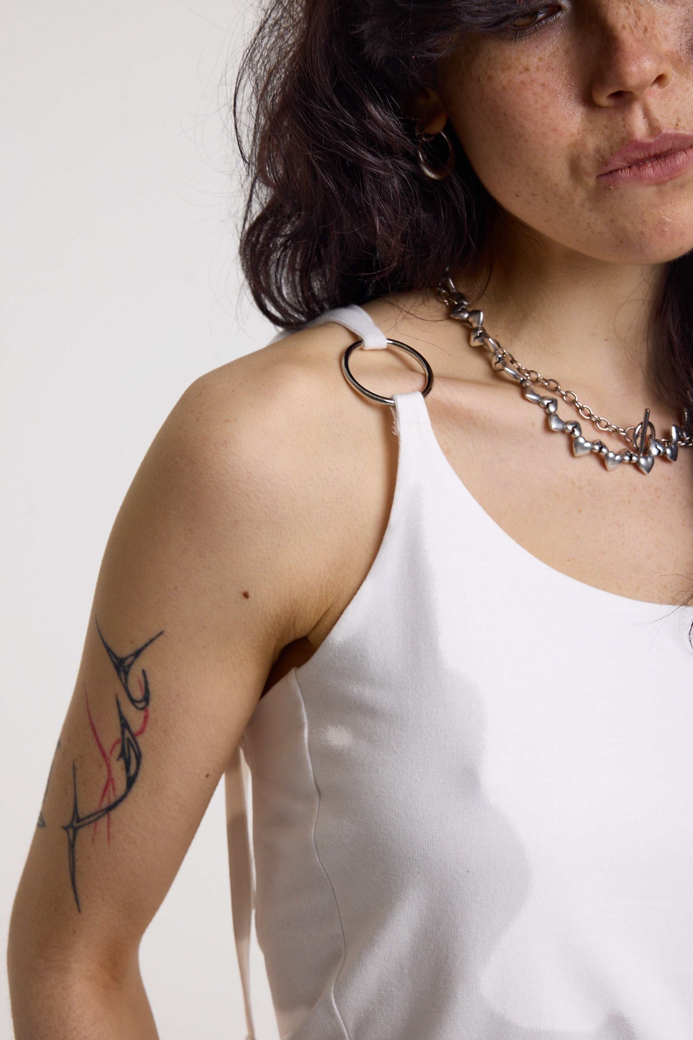 White strappy cami top with tie straps, cowl back and silver O rings, worn by model